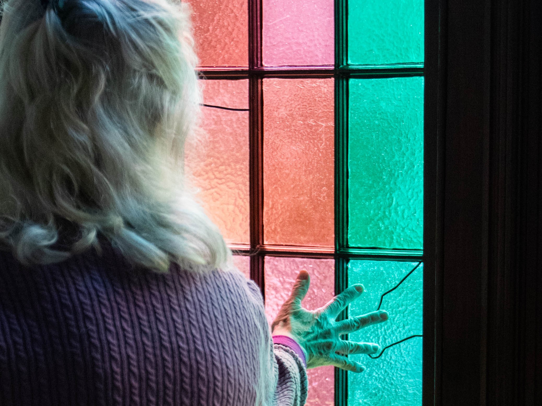 Evelyn Reece touches the interior of a stained glass window in the former Lexington Presbyterian Church earlier this month. The windows were recently restored with the help of funds received from a grant written by Reece. (Photo/Sarah White)