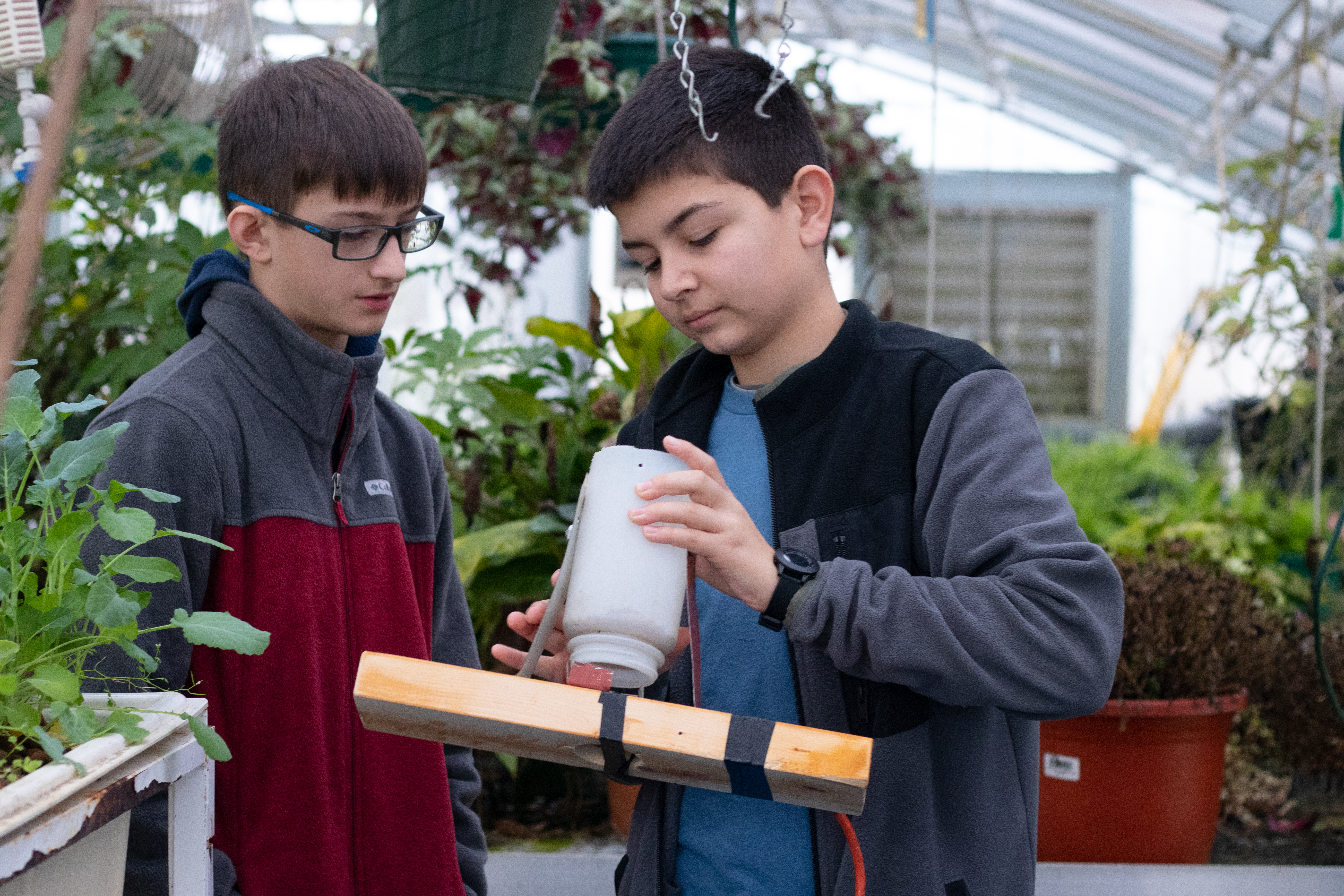 Oglethorpe County Middle School students Cole Fraust (right) and Aidan Dellinger (left) fix the fish-feeding device above the aquaponics system that the students at the middle school maintain. (Julia Walkup/The Oglethorpe Echo) 
