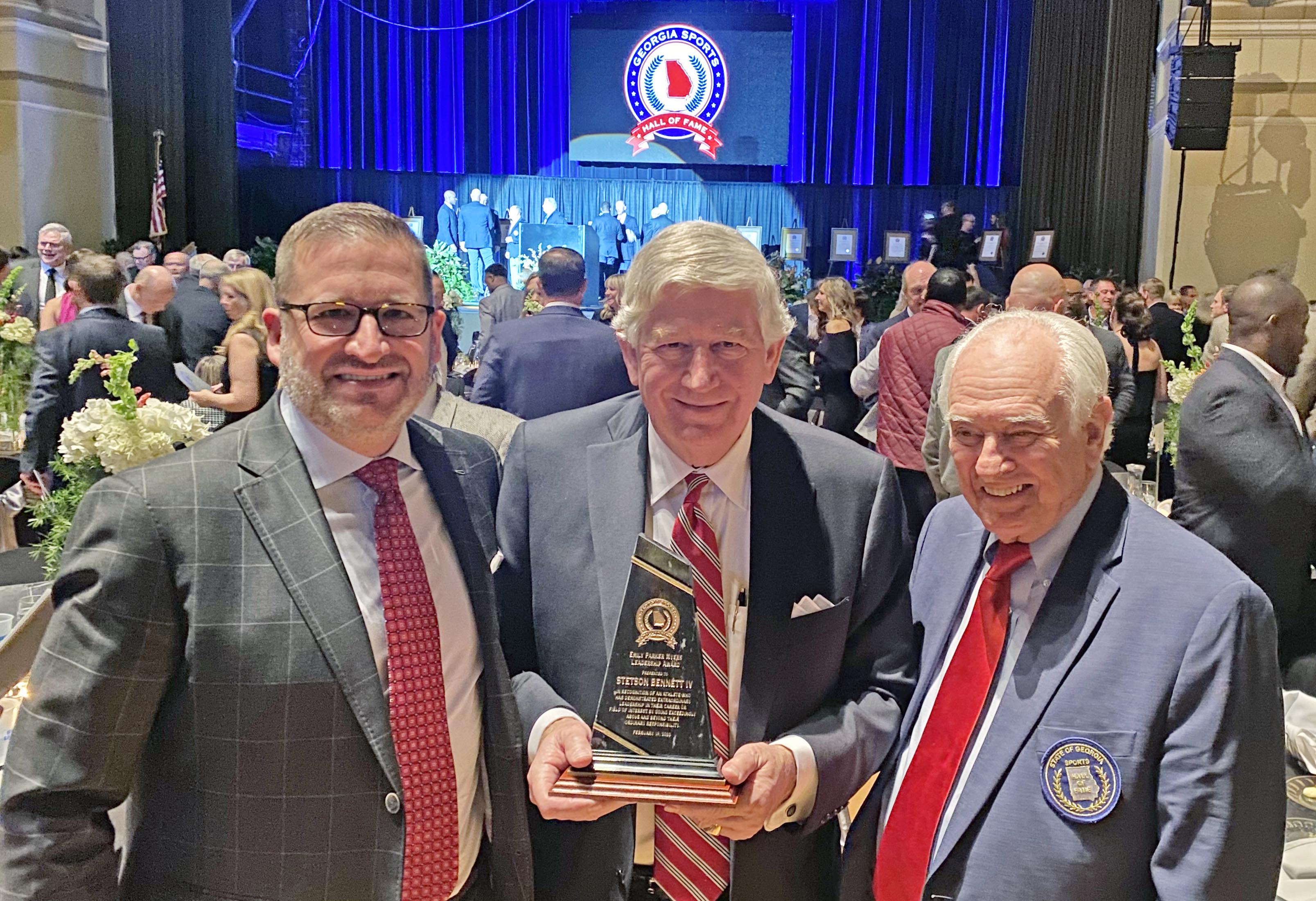 UGA athletic director Josh Brooks (left) and UGA’s Loran Smith flank Dink NeSmith as he displays Stetson Bennett’s leadership award received at the Georgia Sports Hall of Fame banquet on Feb. 19 in Macon. (Jennifer Smith/Submitted Photo)  