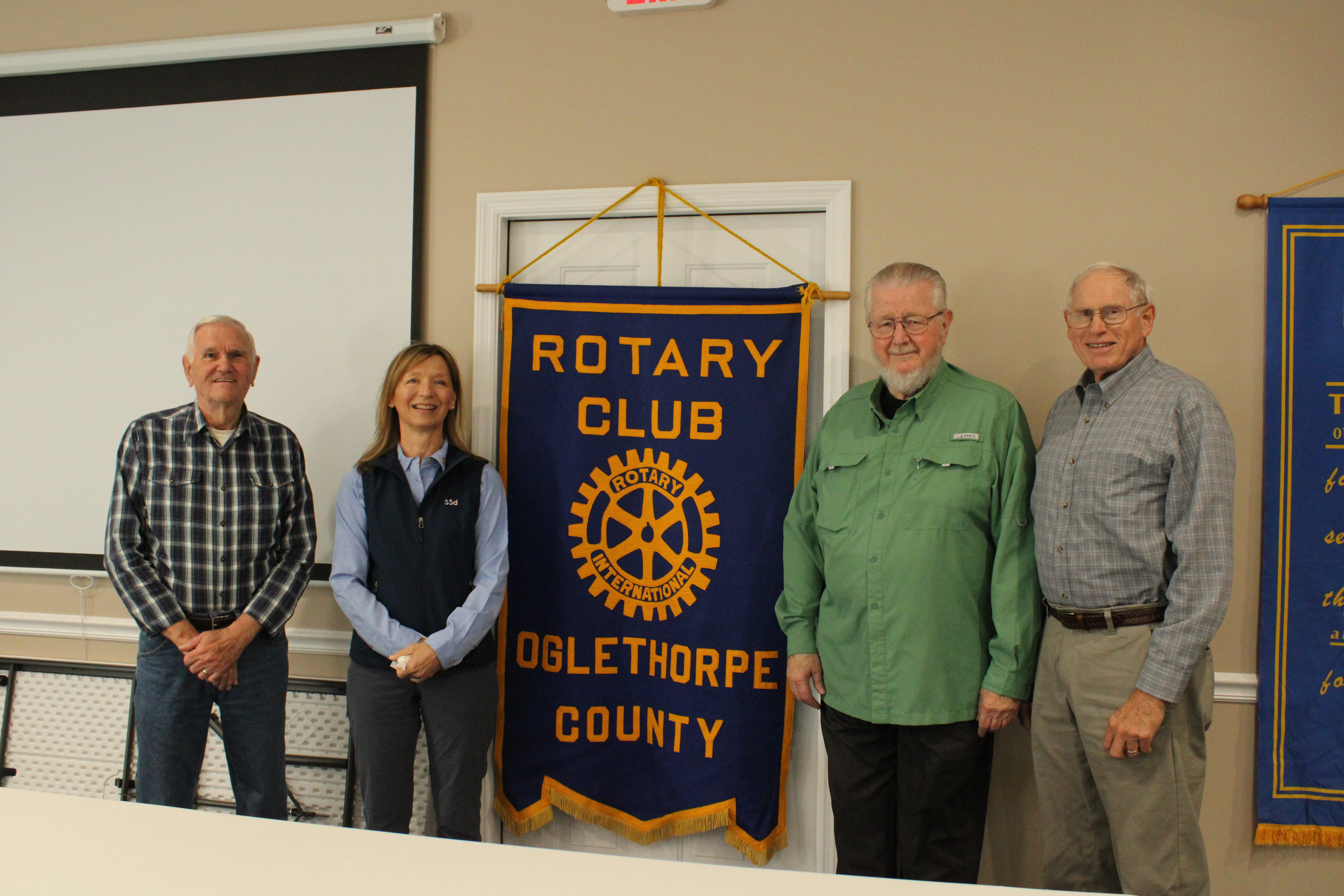 Oglethorpe County Rotary Club founding charter members pose with current president Susan Sharp in front of the chapter’s flag. Roger Neesmith (from left), Sharp, John Stephens and Bill Cabaniss are pictured. (ELOISE MCNAIR/THE OGLETHORPE ECHO