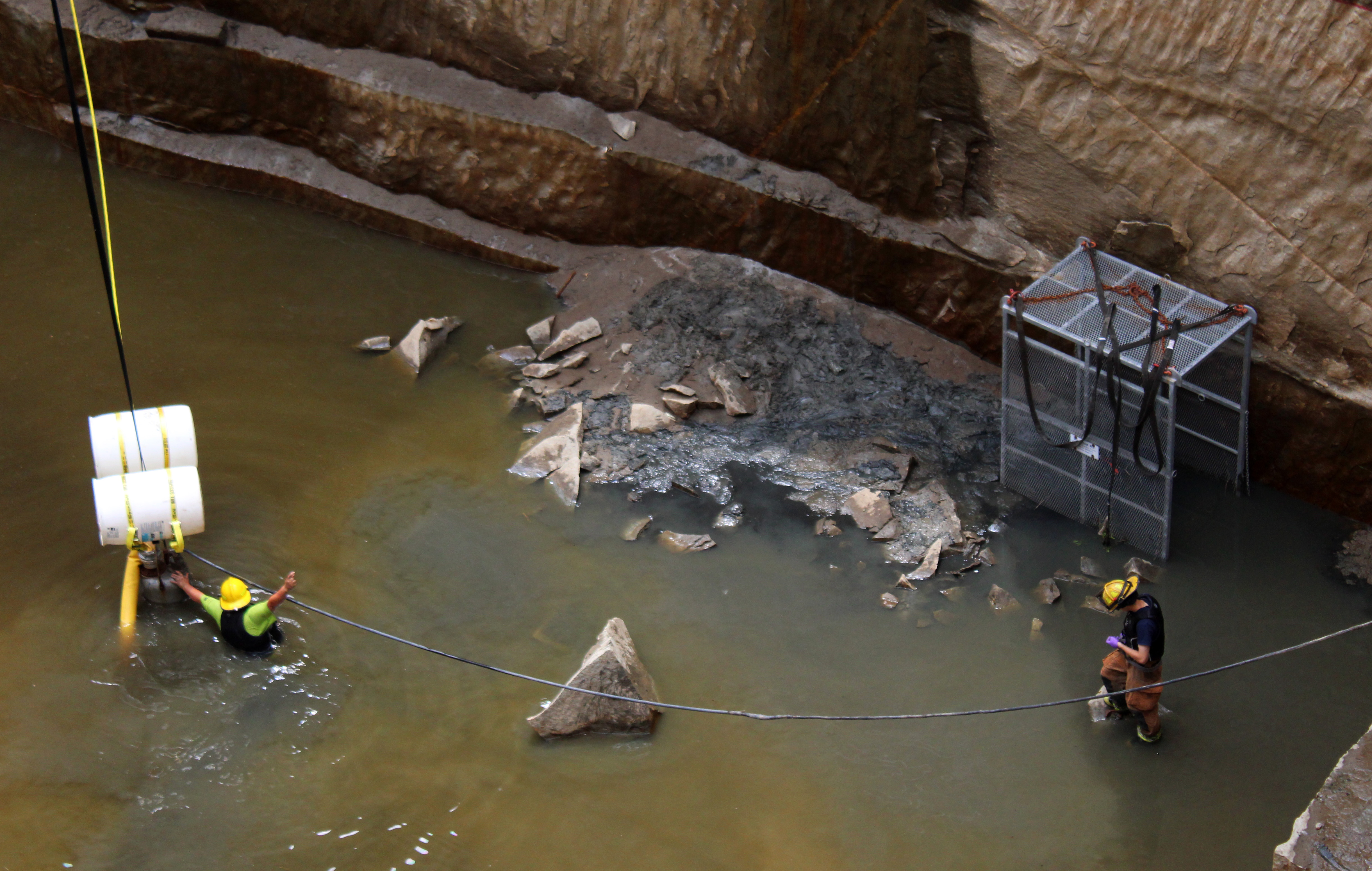 Searchers wade through the remaining water at the bottom of one of the quarries that was drained in the search for Jimmy Anglin's remains. (Photo/Caitlin Farmer)
