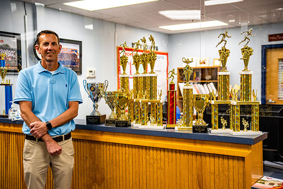 Assistant principal and assistant athletic director William Sampson displays the state and region championship trophies won by OCHS athletic teams this year. (Photo/Jack Casey)