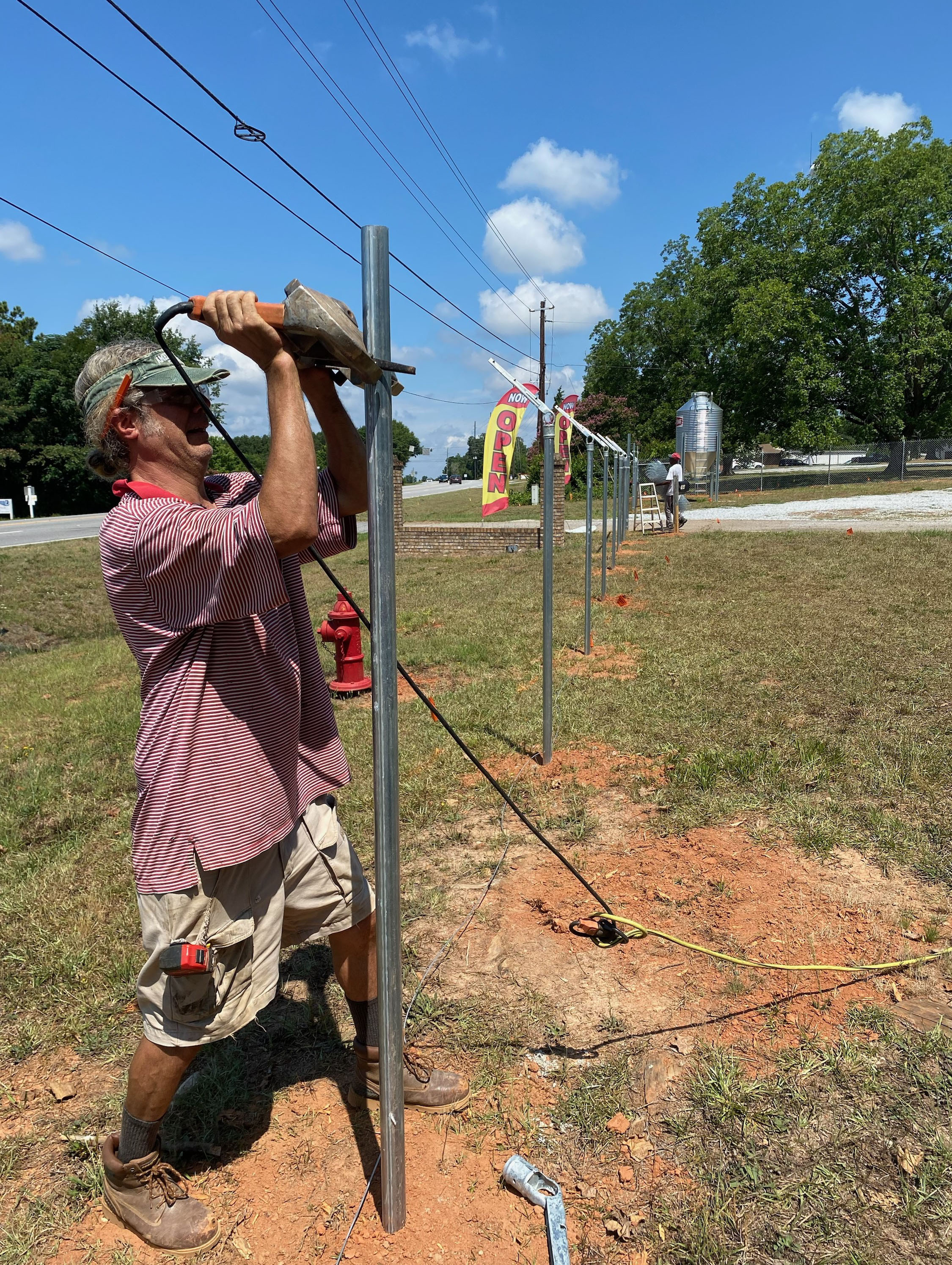 Todd Crowe, foreground, and Jared Johnson of Akridge Fence Company of Arnoldsville install fencing around Patriot Farm Supply on Highway 78. (Photo/Dink NeSmith)