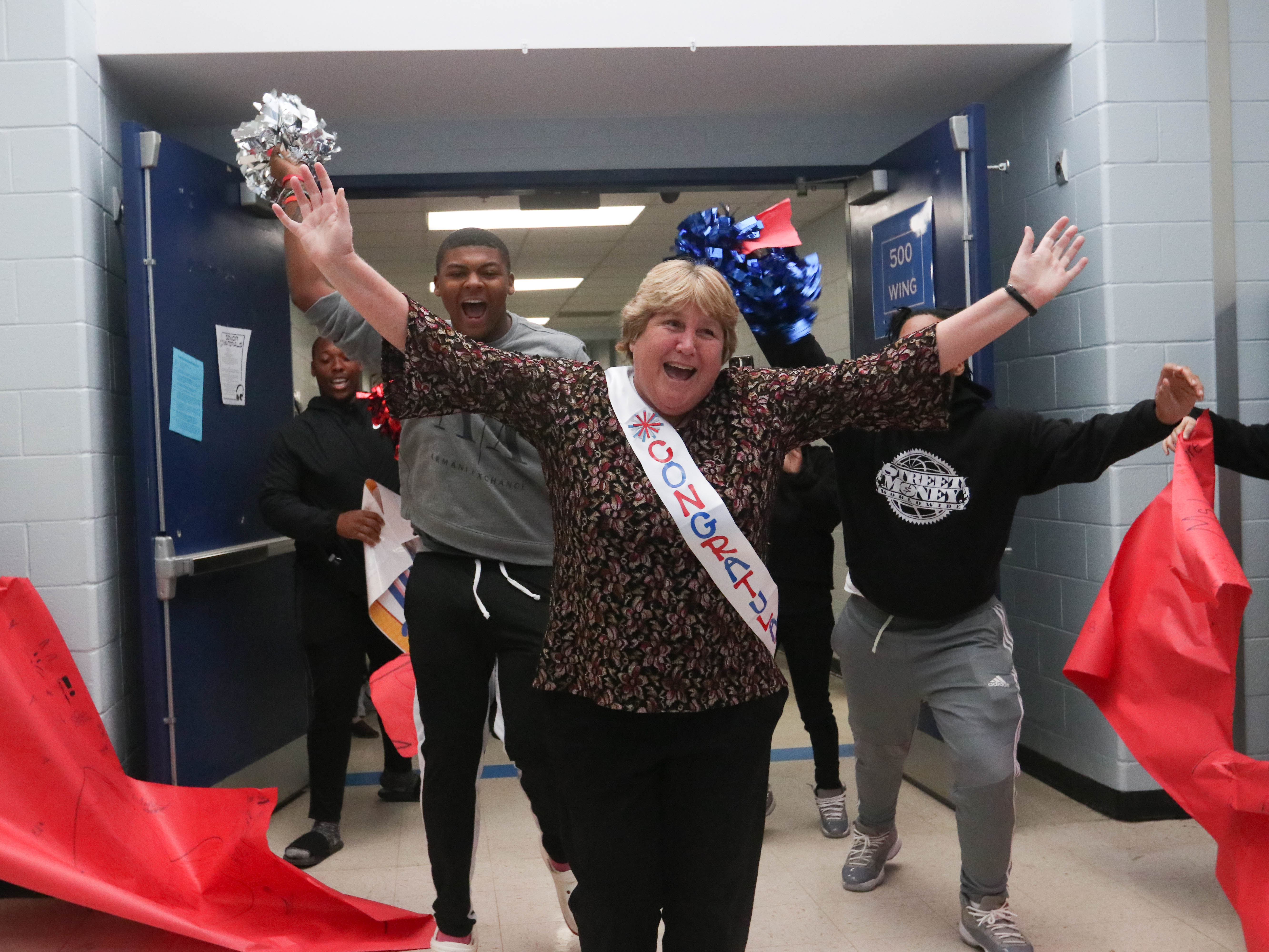 Beverley Levine runs through a paper banner upon entering Oglethorpe County High School as part  of her celebration through the county schools. (Photo/Katie Tucker)
