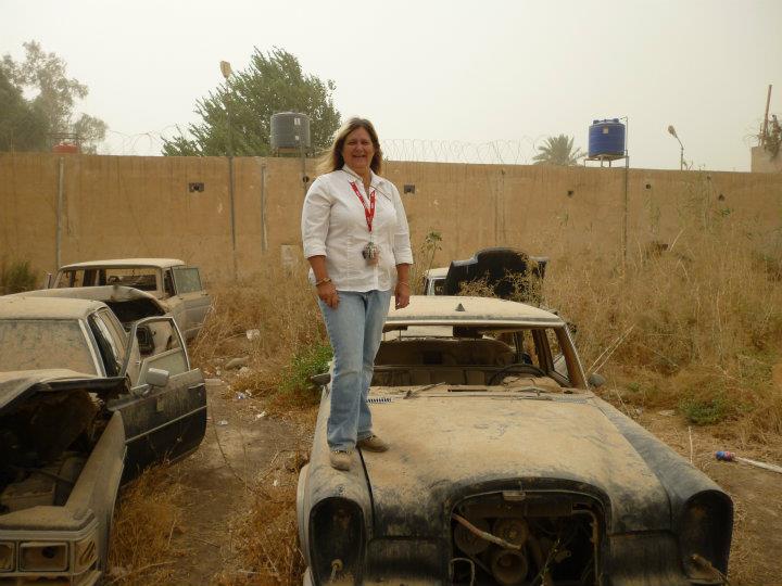(Submitted Photo) Gina Holloway, standing on top of an abandoned vehicle in the Green Zone in Baghdad in 2011, managed a sign shop in Iraq even though she didn’t speak Arabic.