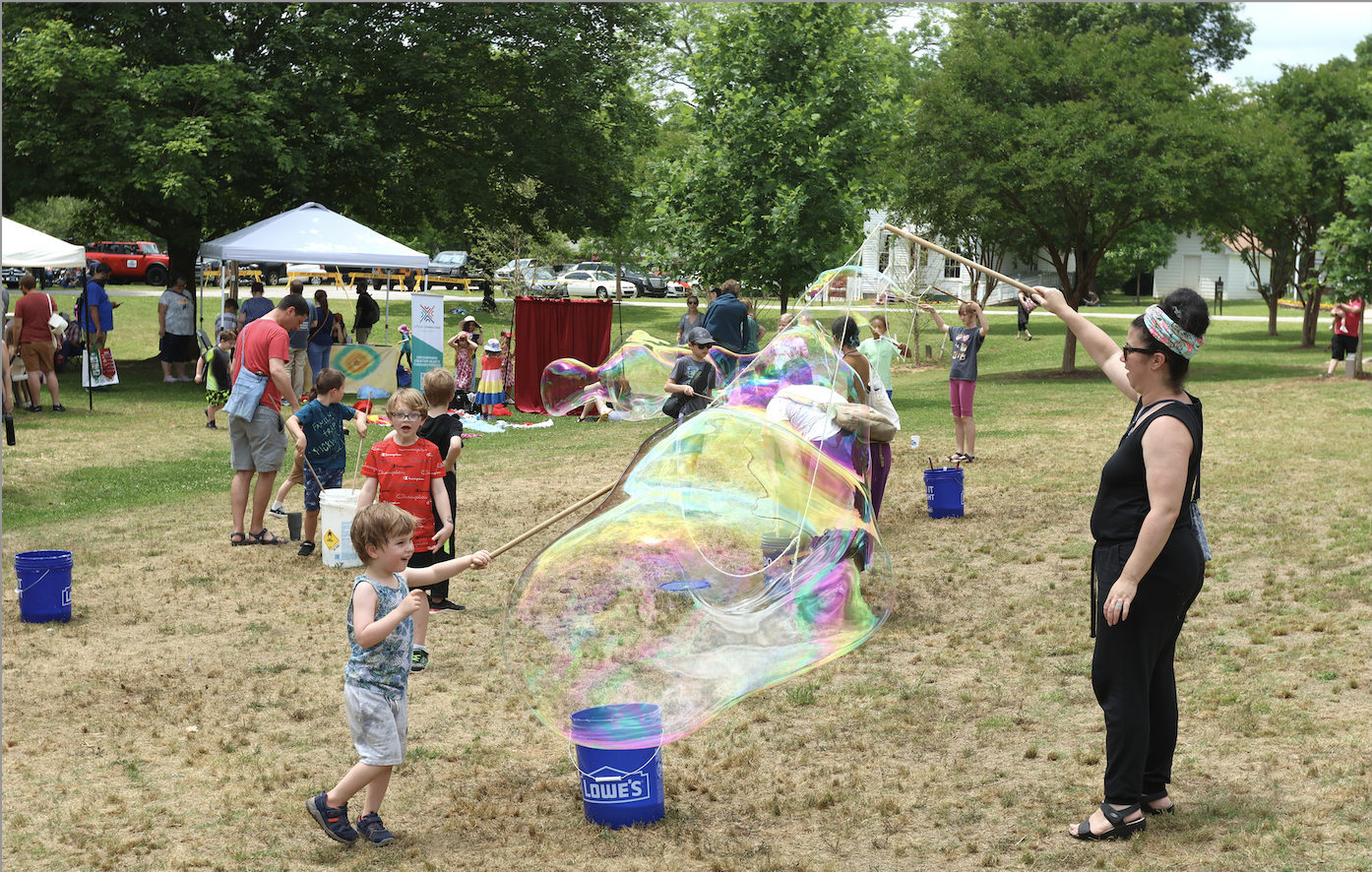 Parents and children play with giant bubbles at the Marigold Festival on Saturday. Kids played in bounce houses and enjoyed face painting, puppet making, games, photo booths and more at the annual event in Winterville. (LANDEN TODD/THE OGLETHORPE ECHO)