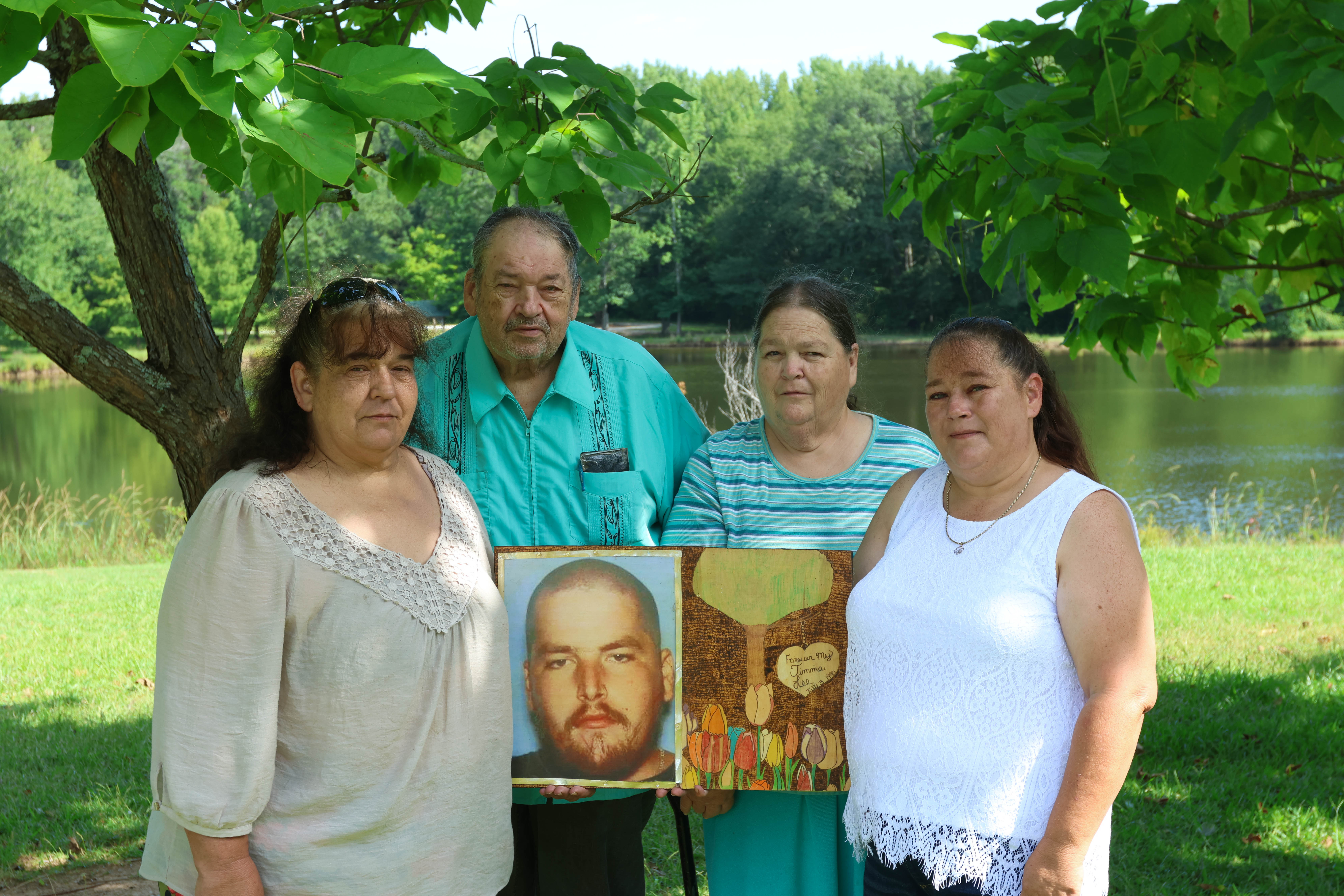 Linda Anglin (from left), Henry Anglin, Vickie Anglin and Kelly Hembrick pose with a photo of Jimmy Anglin at Bryan Park in Crawford last month. The family continues to look for his remains, nearly six years after he went missing in 2017. (LANDEN TODD/THE OGLETHORPE ECHO)