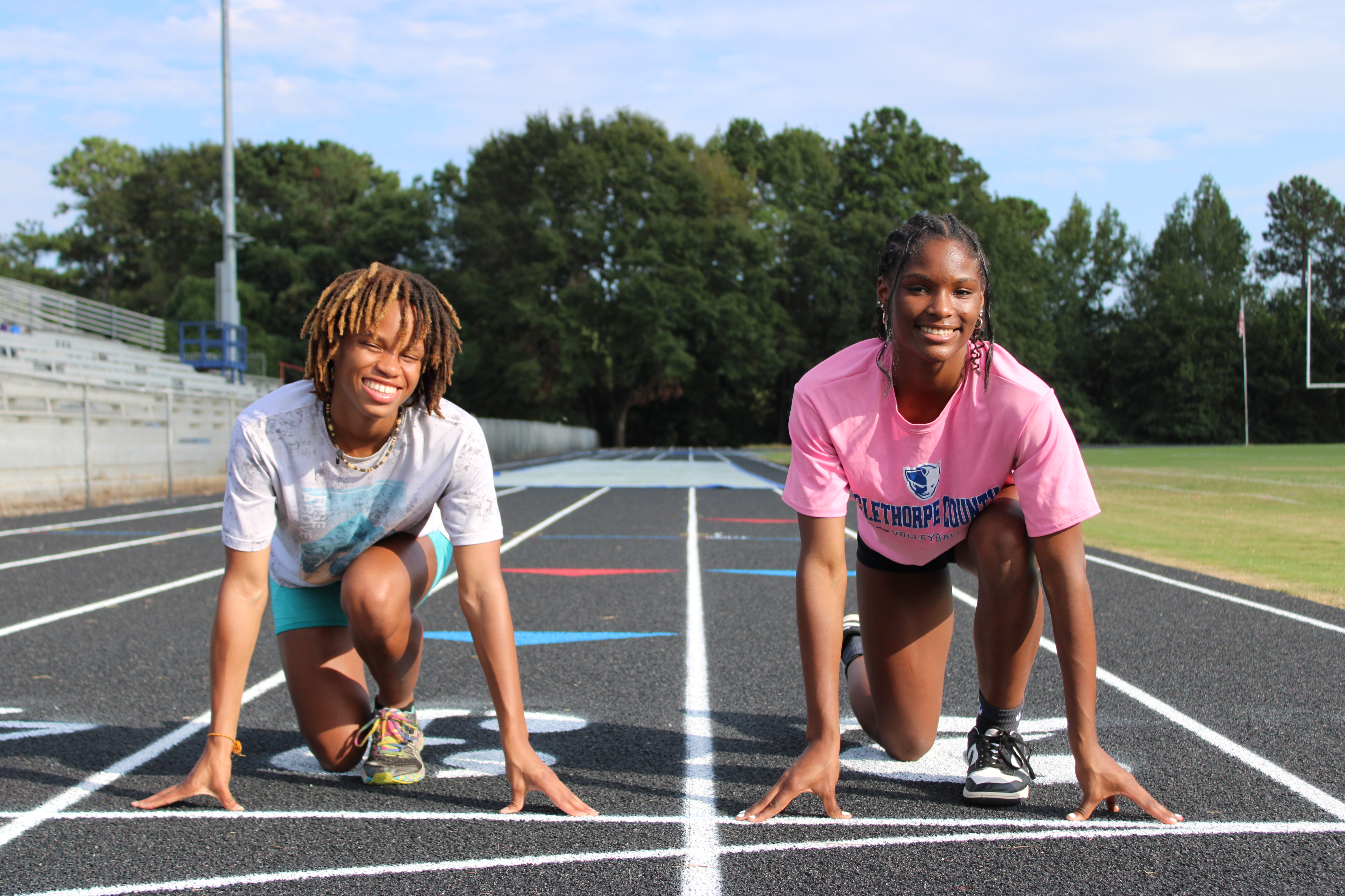 Sydnie (left) and Kenzie Henderson smile as they show off their track starting positions. The fraternal twins are star athletes in several sports at Oglethorpe County, including volleyball, cross country, basketball and track. (LAUREN HILL/THE OGLETHORPE ECHO)