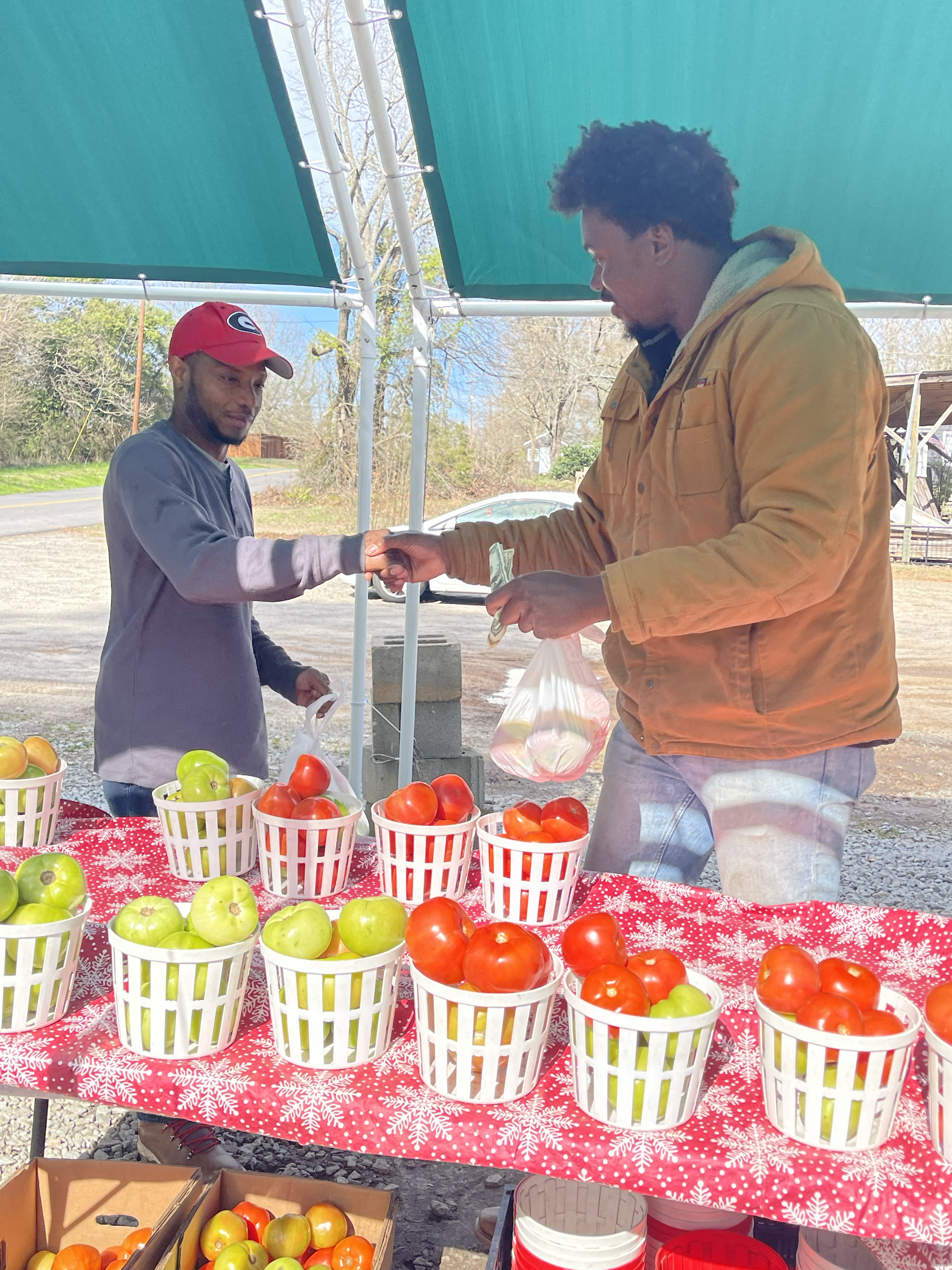 Donald Randall, left, and Kendall Strickland, right, shake hands after Randall buys vegetables from Strickland's stand in February. Strickland Pride Produce will be moving on Feb. 5 from its current stand in downtown Lexington to 1129 Athens Road in Crawford. (Destiny Hartwell/The Oglethorpe Echo)