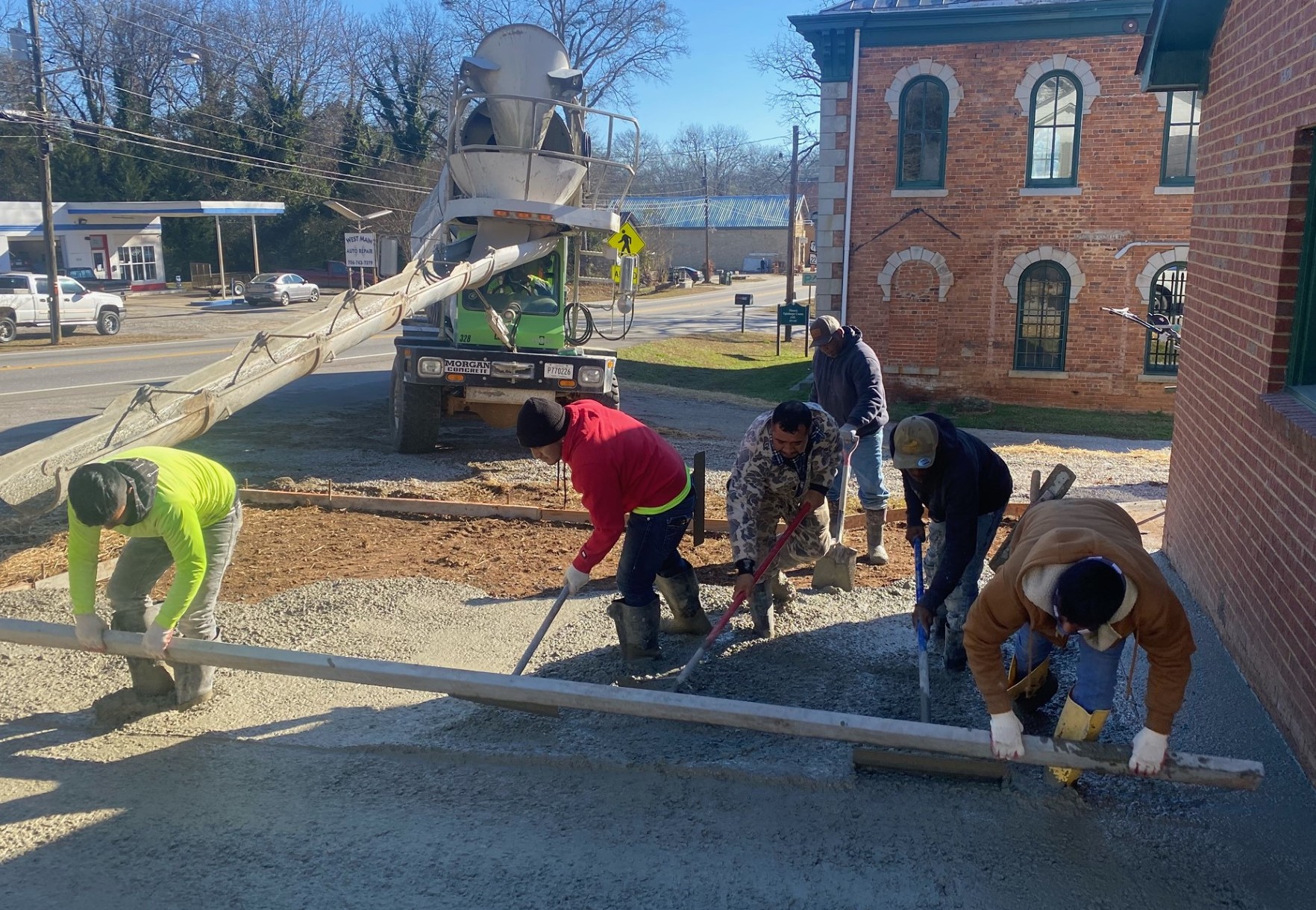 Workers pour concrete for the accessible parking lot at Lexington's new City Hall, which is on the other side of the old jail from the previous City Hall. (Dink Nesmith/The Oglethorpe Echo)