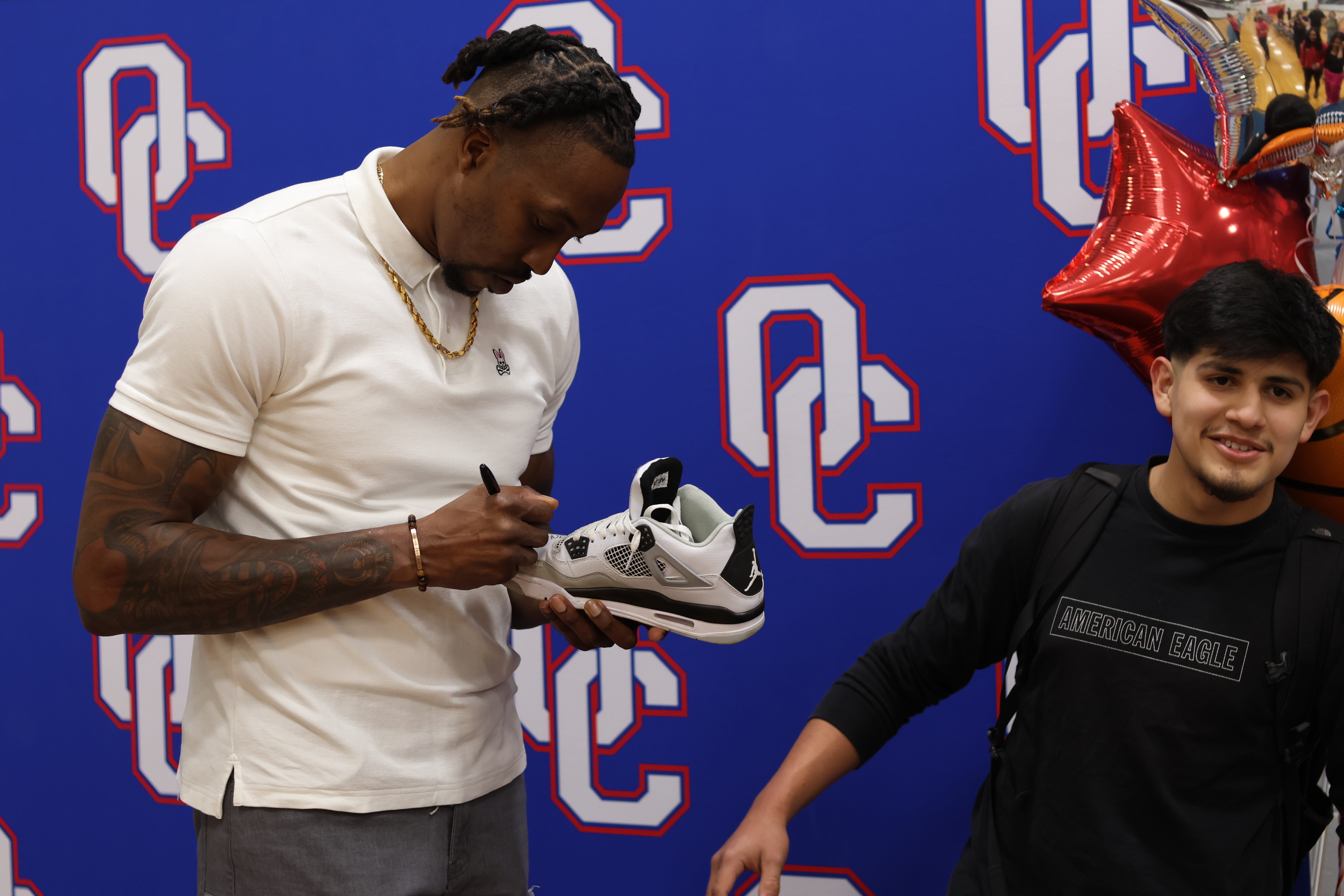 Former NBA star Dwight Howard Jr. signs OCHS student Henry Manuel Hernandez’s sneaker in the school’s gym on March 21. Howard and several others spoke to students about the importance of life coaches to start the Patriot Promise program. (Jim Bass/The Oglethorpe Echo)