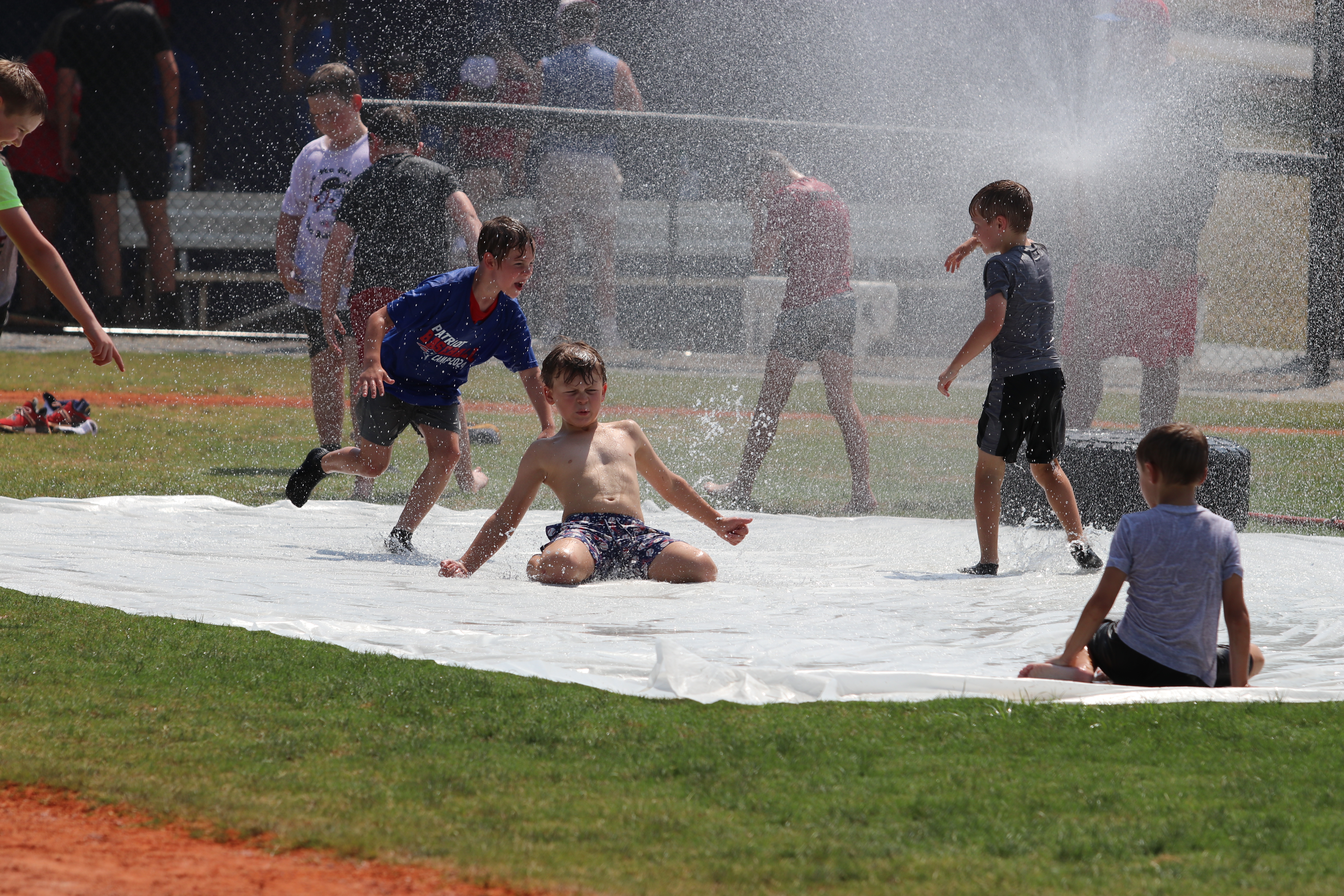 Lawson Smith (center) and other campers imitate a soccer “knee slide” goal celebration on the slip-n-slide after the baseball finished on June 26. OCHS baseball coach Mike Campbell focused on having fun at the camp. (Torin Smith/The Oglethorpe Echo)