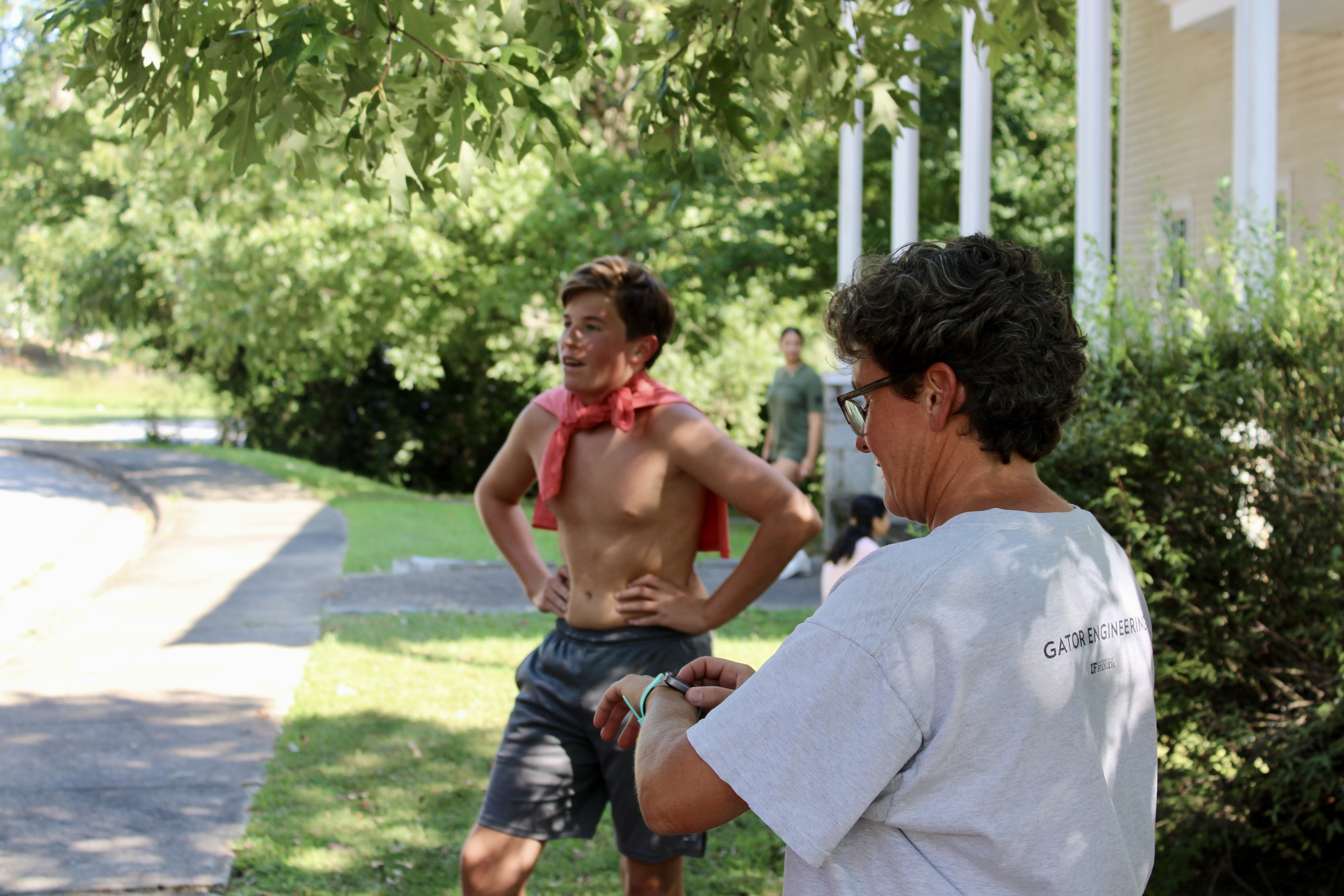 Head coach Jessica Ward checks the time as the first runner, freshman Dylan Minthorn, returns from his run at practice on Thursday, Aug. 22, 2024. The team rotates practice routes during the season to gain experience on different surfaces and with differing millage. (Audrey Pfitzner/The Oglethorpe Echo)