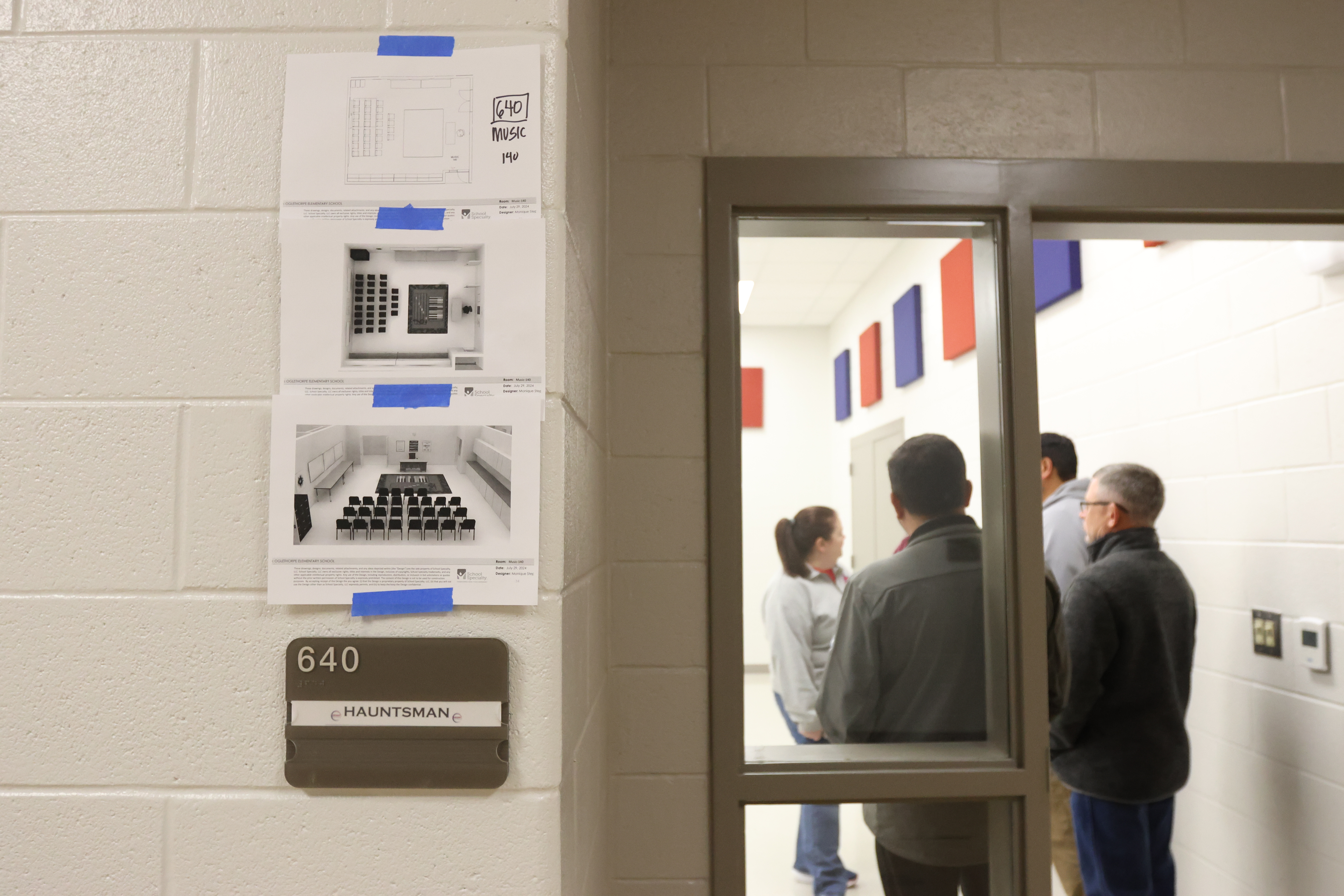 Seating diagrams and room layouts are taped to the side of the wall outside the door to a classroom at the new Oglethorpe County Elementary School as BOE members look around. (Avni Trivedi/The Oglethorpe Echo)