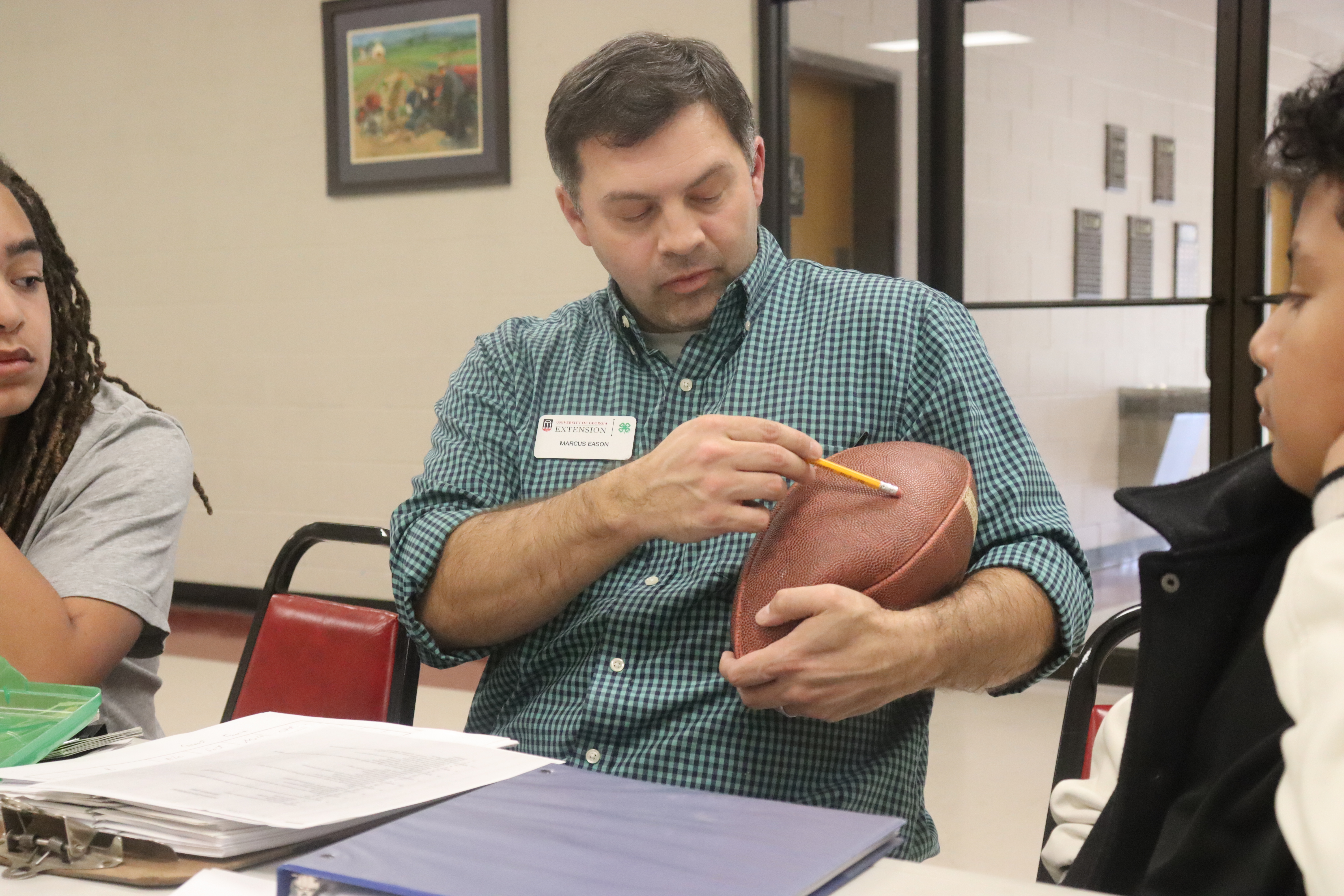 Marcus Eason, Oglethorpe County 4-H youth program director, holds a football to demonstrate where to measure and identify features on a live bird during poultry judging practice. The 4-H office hasn’t been able to secure live birds for practice due to avian flu. (Photo/Lilly Stone))
