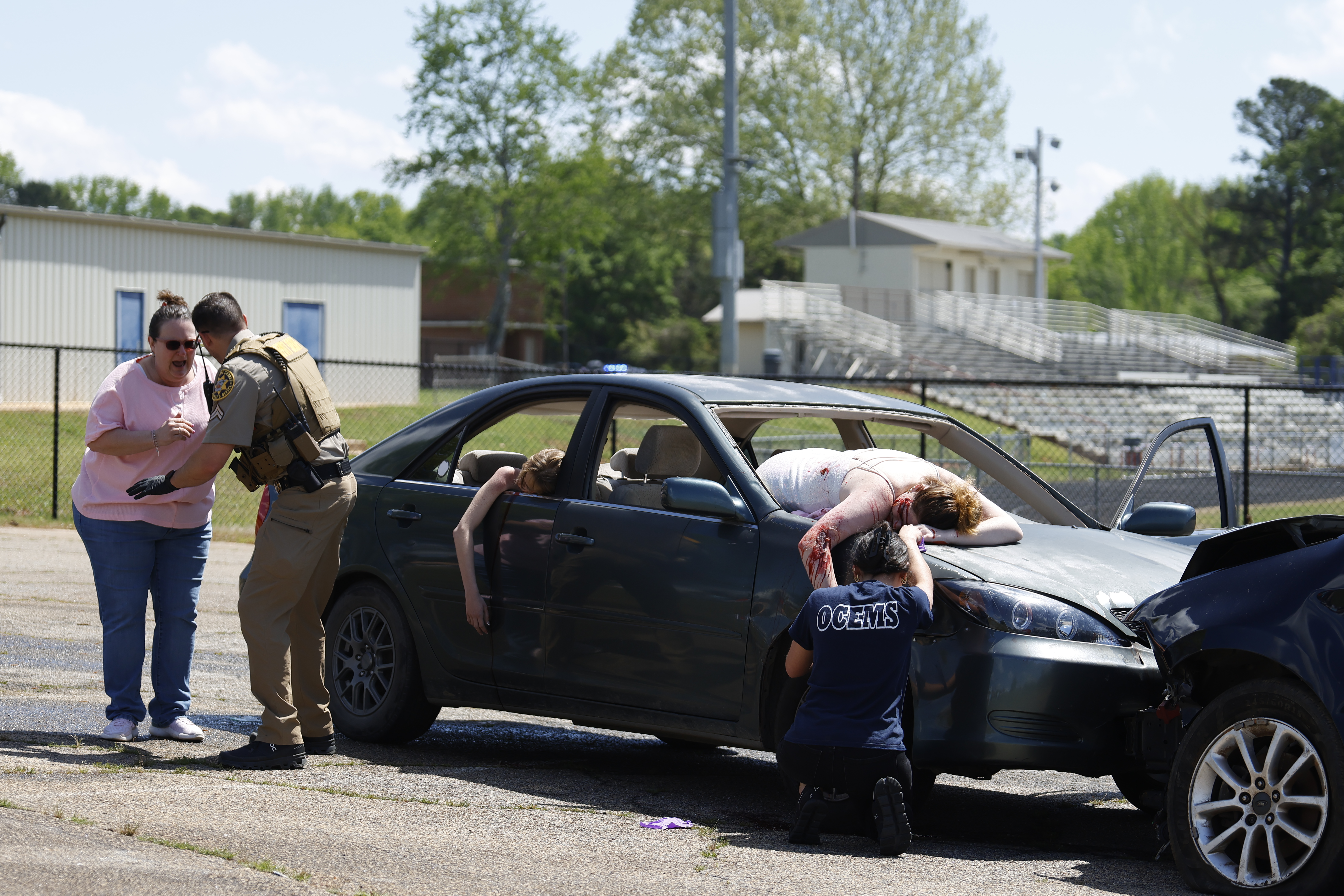 Julie Noltensmeier has to be held back by SRO Kevin Wright as her daughter Sarah Noltensmeier was “ejected” during a mock car accident scene at OCHS last Friday. Noltensmeier (right) is being held by her best friend Smyth Hamby as part of Ghost Out. (Photo/Frankie Hennessy)