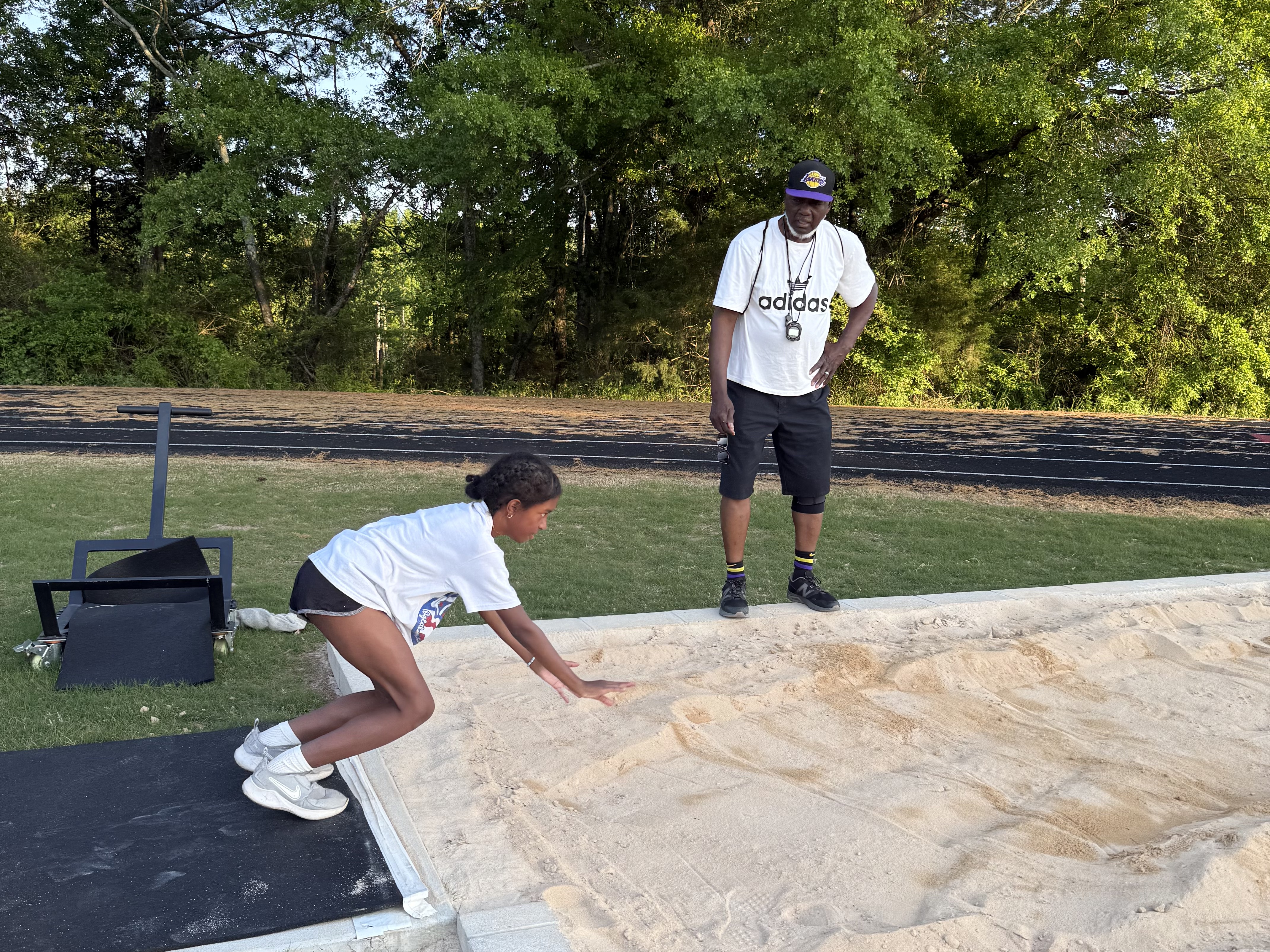 Brielle Jones bends her knees in preparation to jump into the standing jump pit as Dwight Howard Sr. watches on April 17. Jones won the fourth heat of the girl’s standing long jump event at the North Georgia Youth Track and Field Championship on April 19. (Photo/Anna Izquierdo)