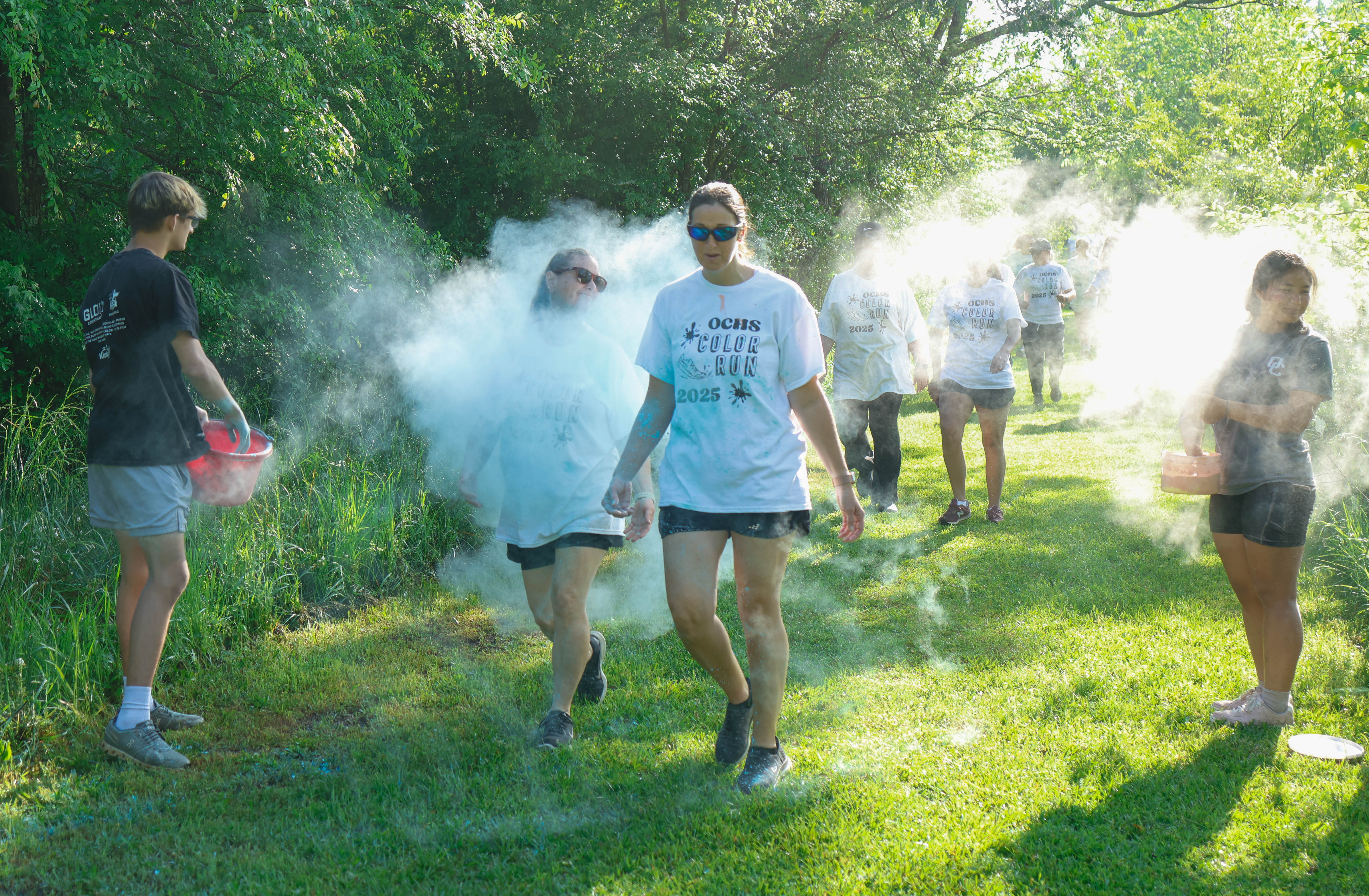 Aidan Dellinger (left), a junior student at Oglethorpe County High School, and Su Moo (right), a senior student at Oglethorpe County High School, throw chalk at runners as they run along the Oglethorpe County High School Color Run in Oglethorpe County, Georgia, on Saturday, April 26, 2025. In total, roughly 40 runners signed up to run in the Color Run, each contributing to funding The CAYA House. (Photo/Felix Scheyer)