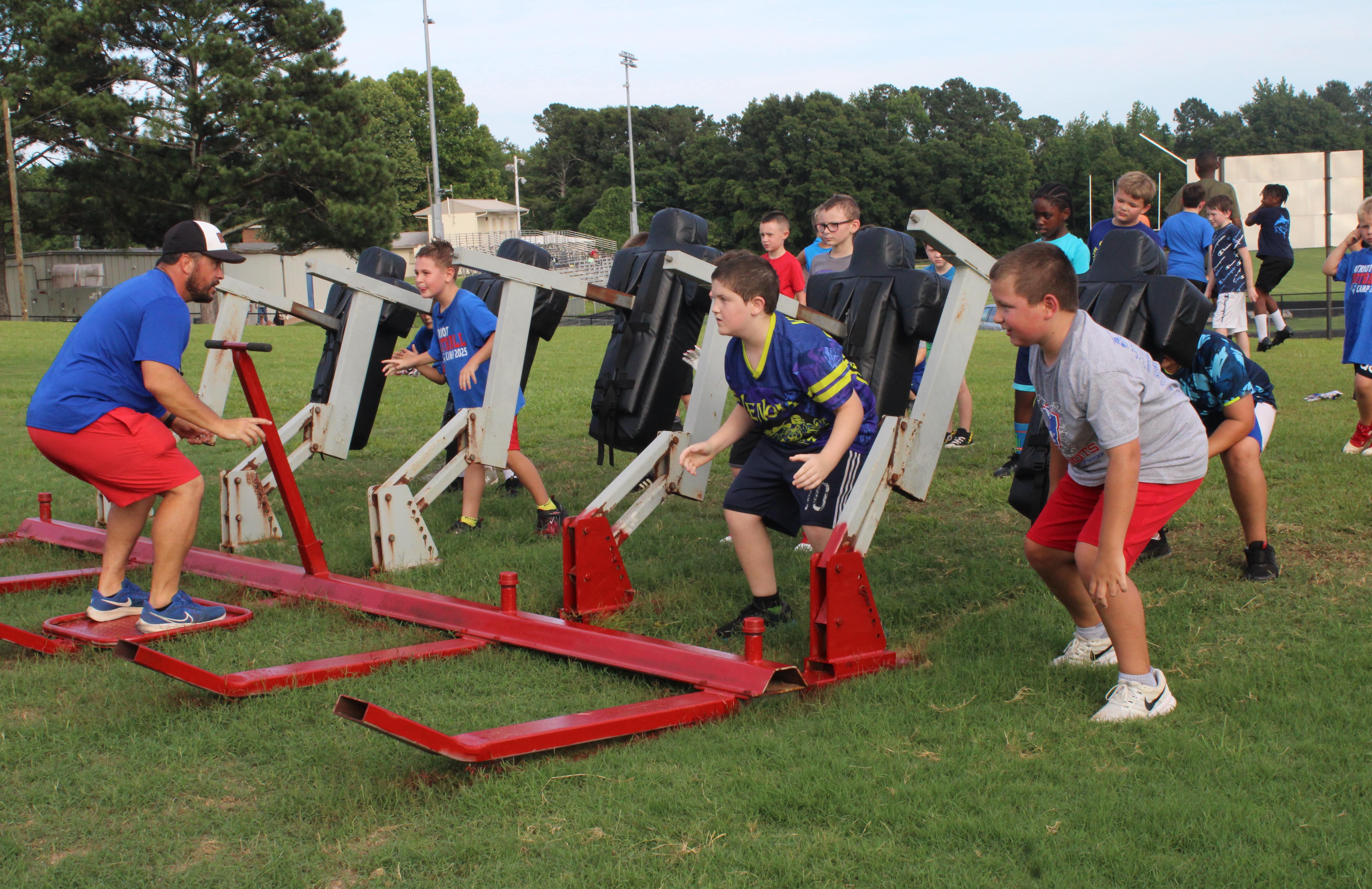 Oglethorpe County football coach Mike Holland instructs campers during offensive line drills on a blocking sled at a practice field near Patriot Stadium at the Oglethorpe County Rec Department’s youth football camp on June 19. (Photo/Elizabeth Kim)
