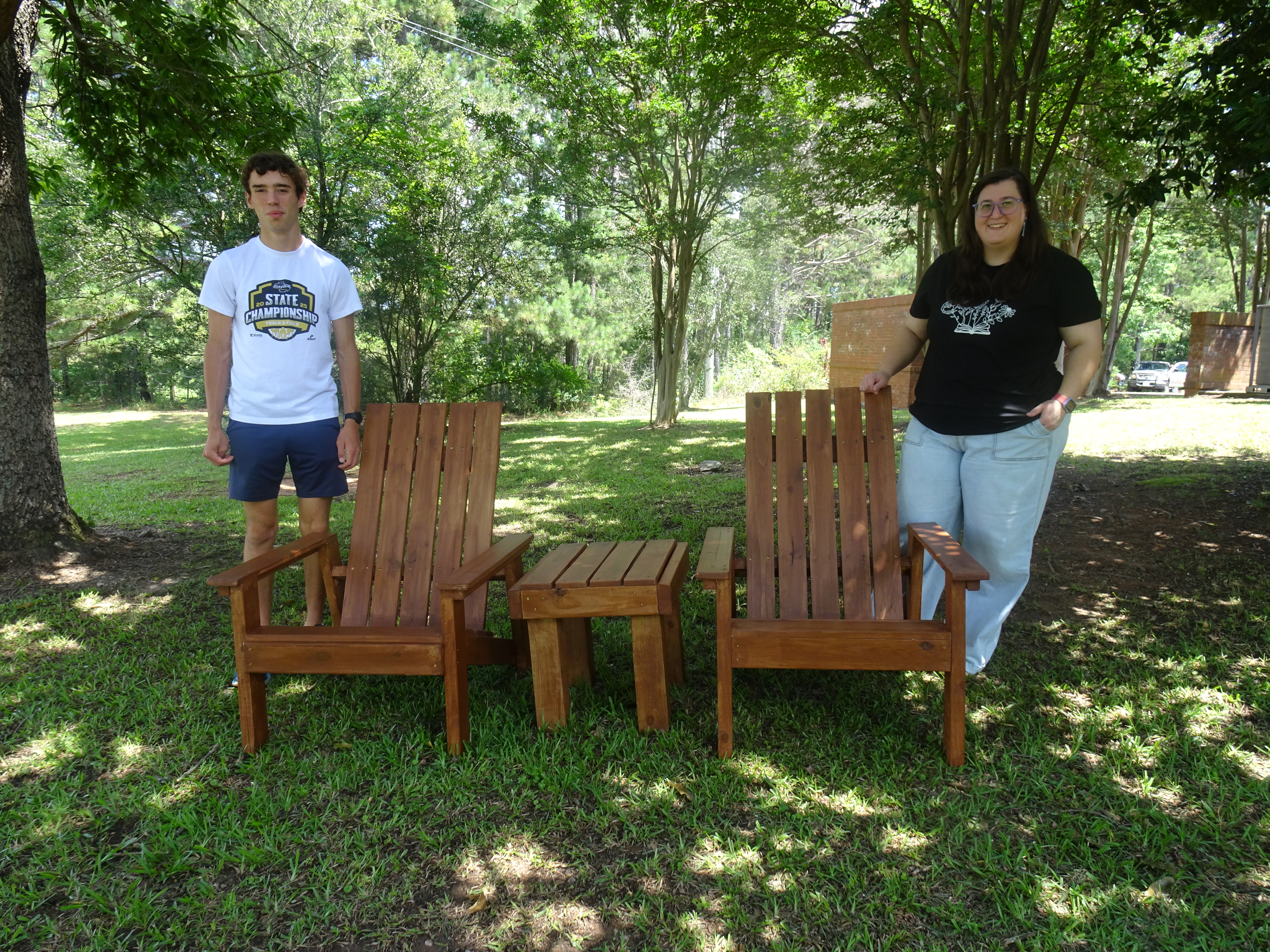 Cory Tillman (left) and library branch manager Nicole Hensley stand with the handcrafted patio set that he helped build as part of his Eagle Scout project. The chairs are an addition to plans to expand the library's patio area. (Photo/Elizabeth Kim)