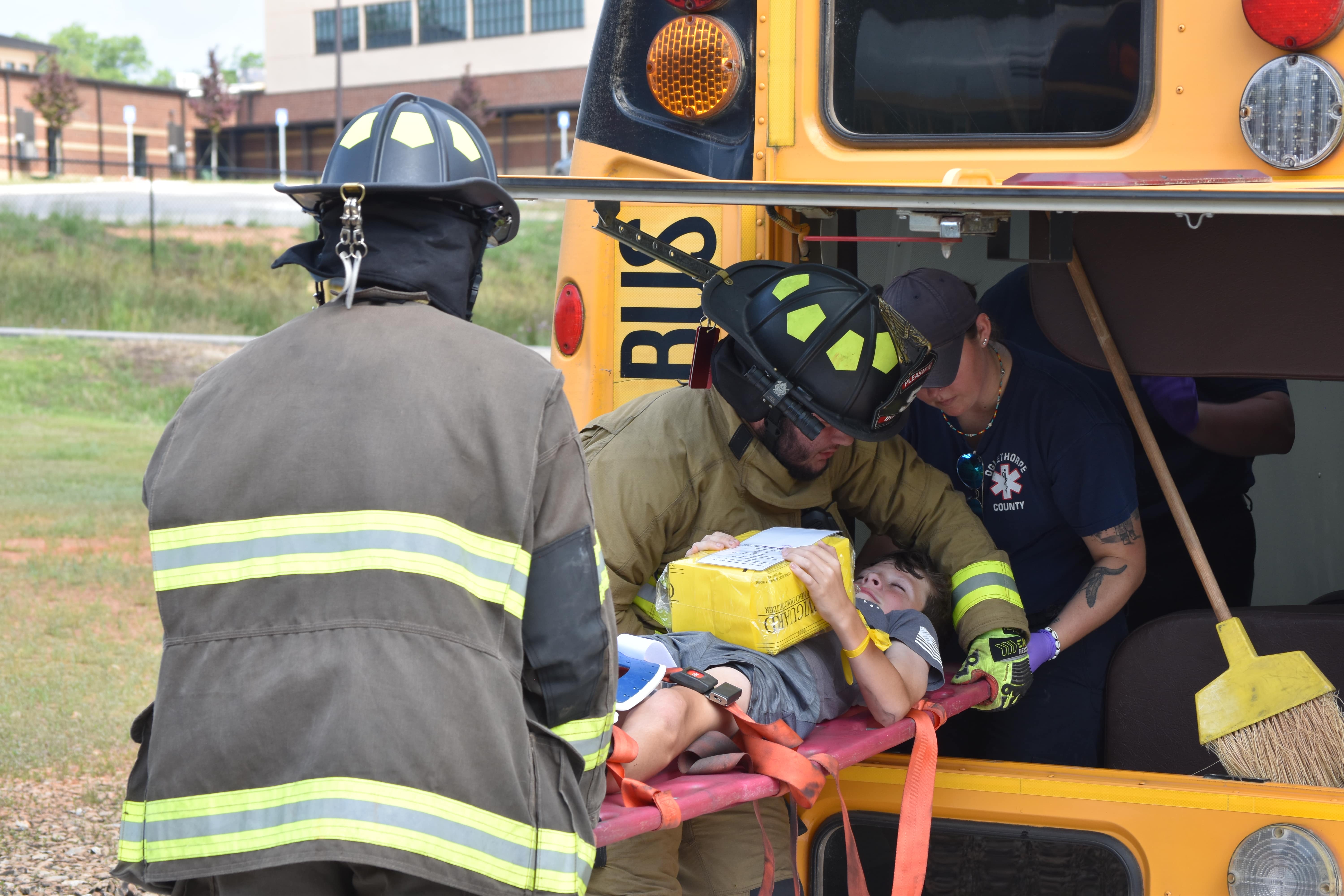 First responders pull volunteer students and a bus driver from a flipped school bus during the EMA’s mass casualty exercise on Saturday. The volunteers stood in for injured students and their parents. (Photo/Emma Greene)