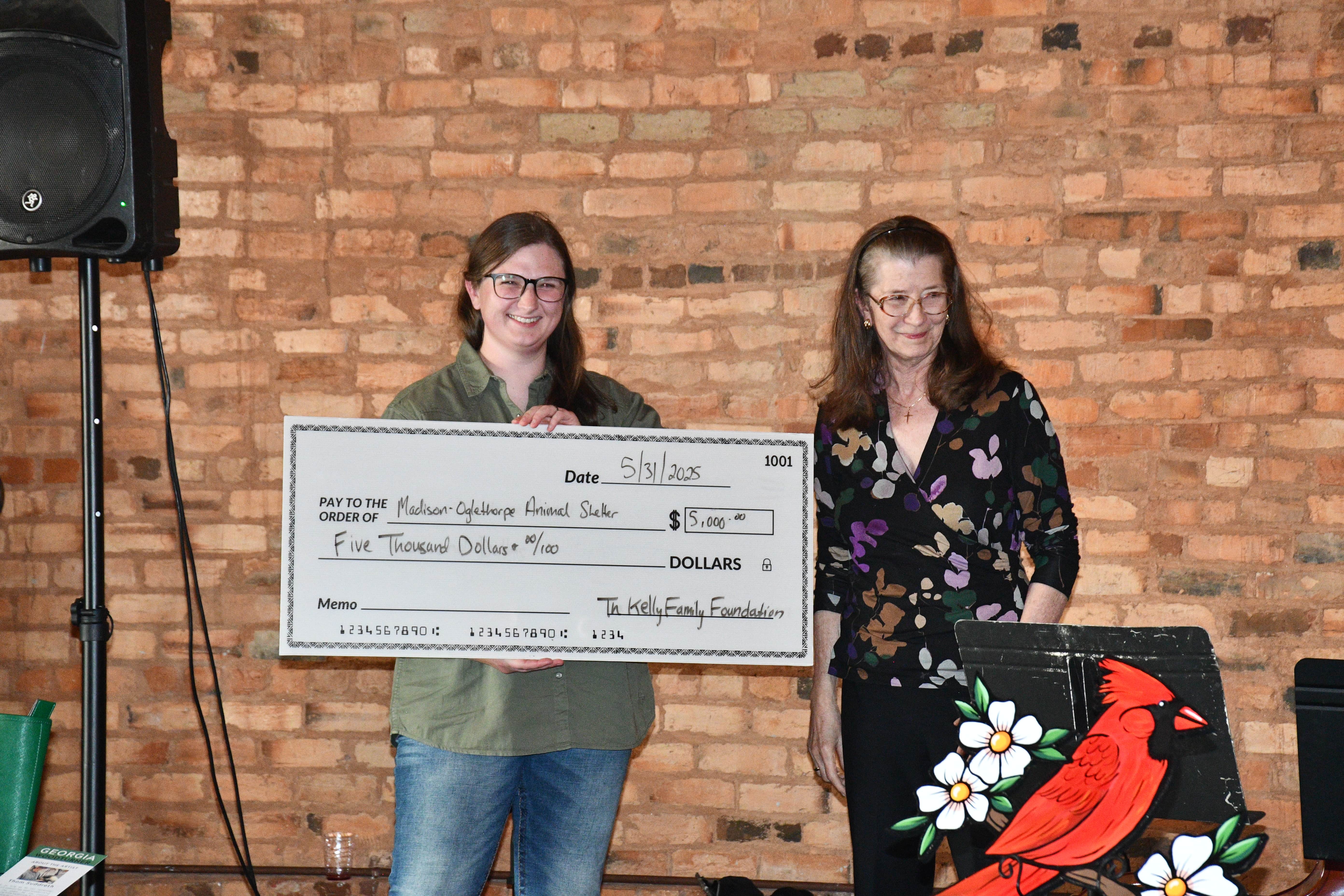 MOAS director Juli Huth holds a $5,000 donation from Linda Kelly of The Kelly Family Foundation. The foundation gives an annual donation to the shelter. (Photo/Jennifer Xia)