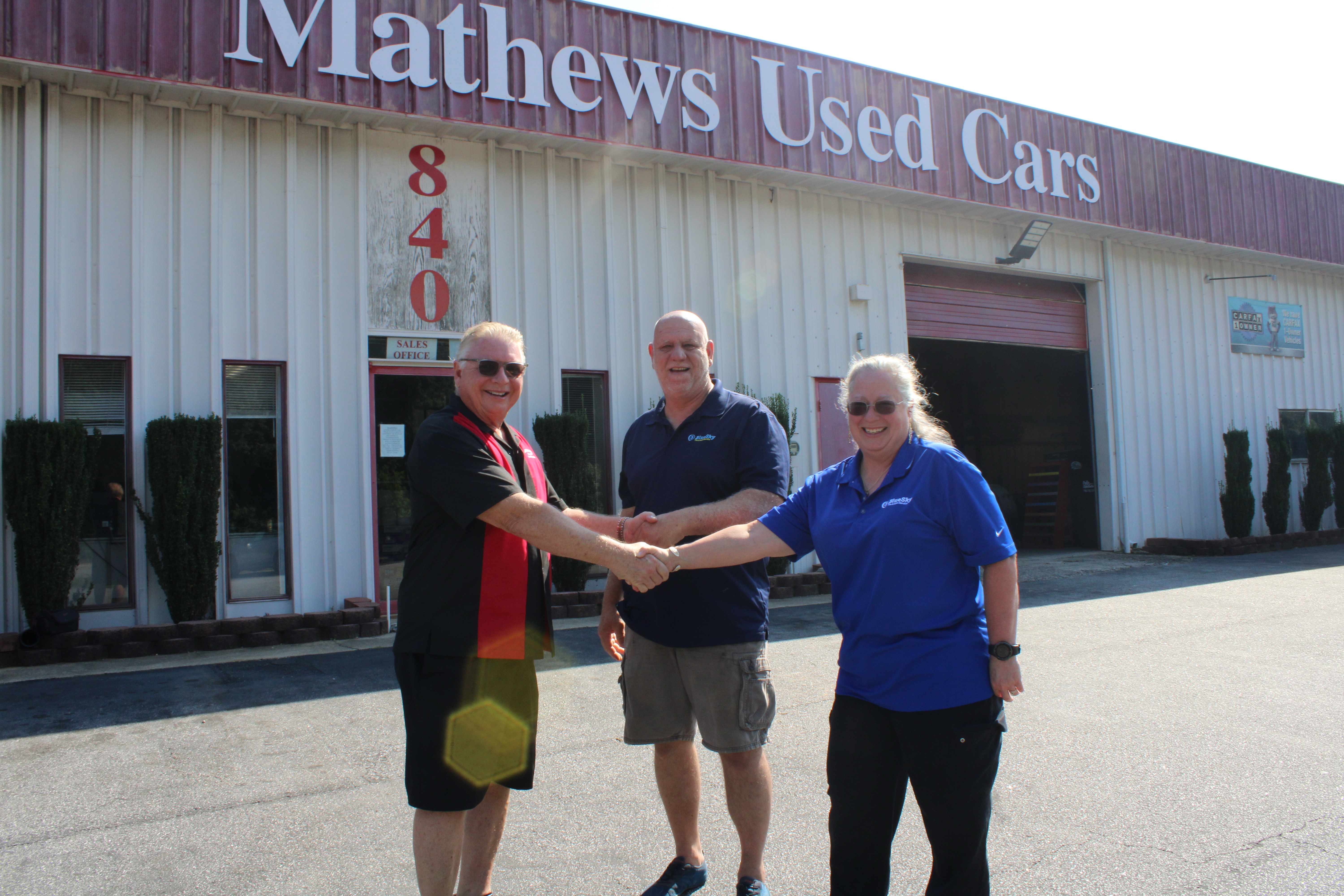Rick Skoglund (left) hands over the keys to the property of Mathews Used Cars to Mike and Mari Robb, the new owners. The dealership has been in business since 1965, with Skoglund buying it from Raymond Mathews in 2010. (Photo/Elizabeth Kim)