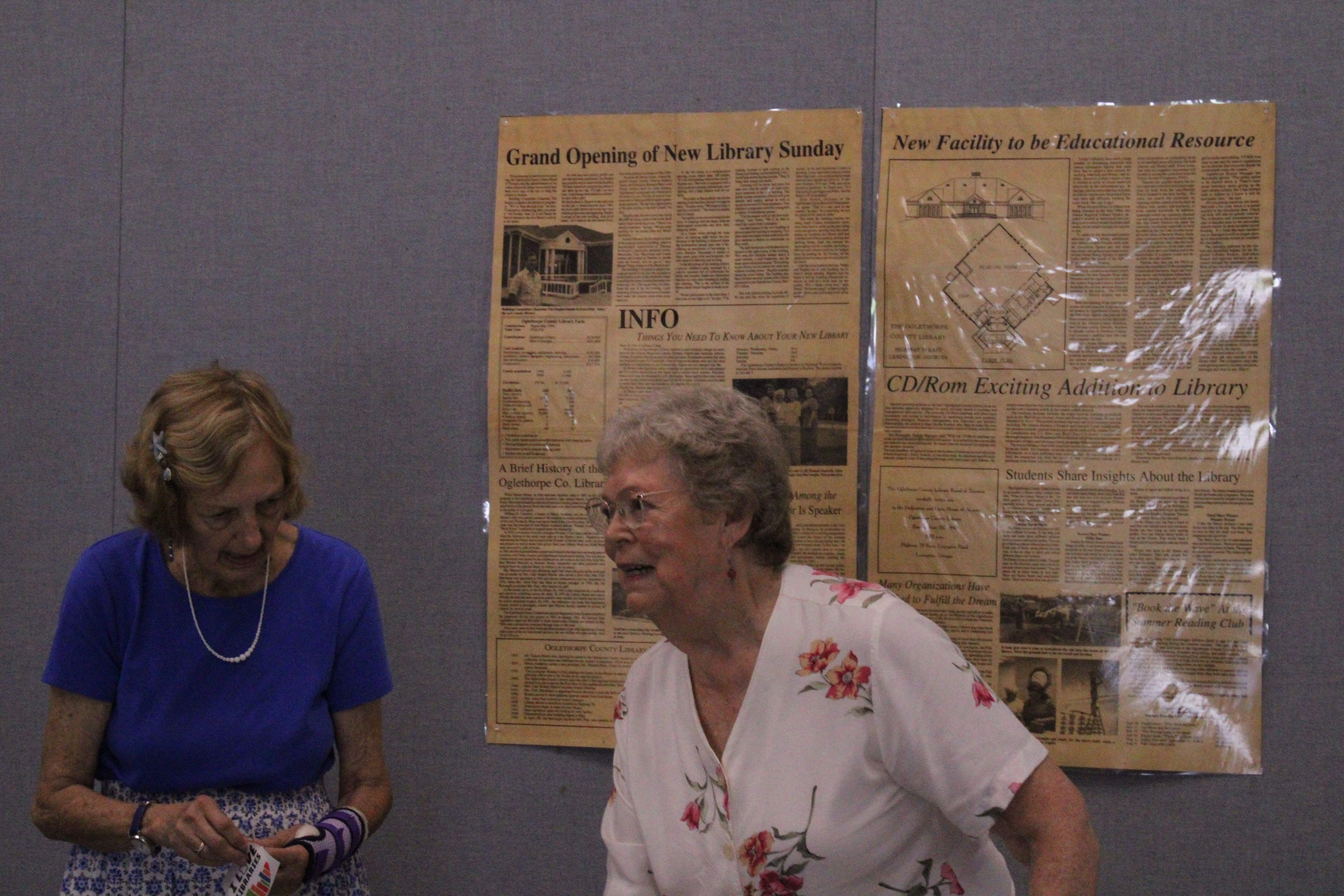 Former staff, board members and volunteers, including Peggy Hroma (left) and Jane Bowen (right), share memories of when the library opened in 1995. Articles from The Echo announcing the construction and opening of the library give information on the building’s cost and resources available to the public. (Photo/Elizabeth Kim)