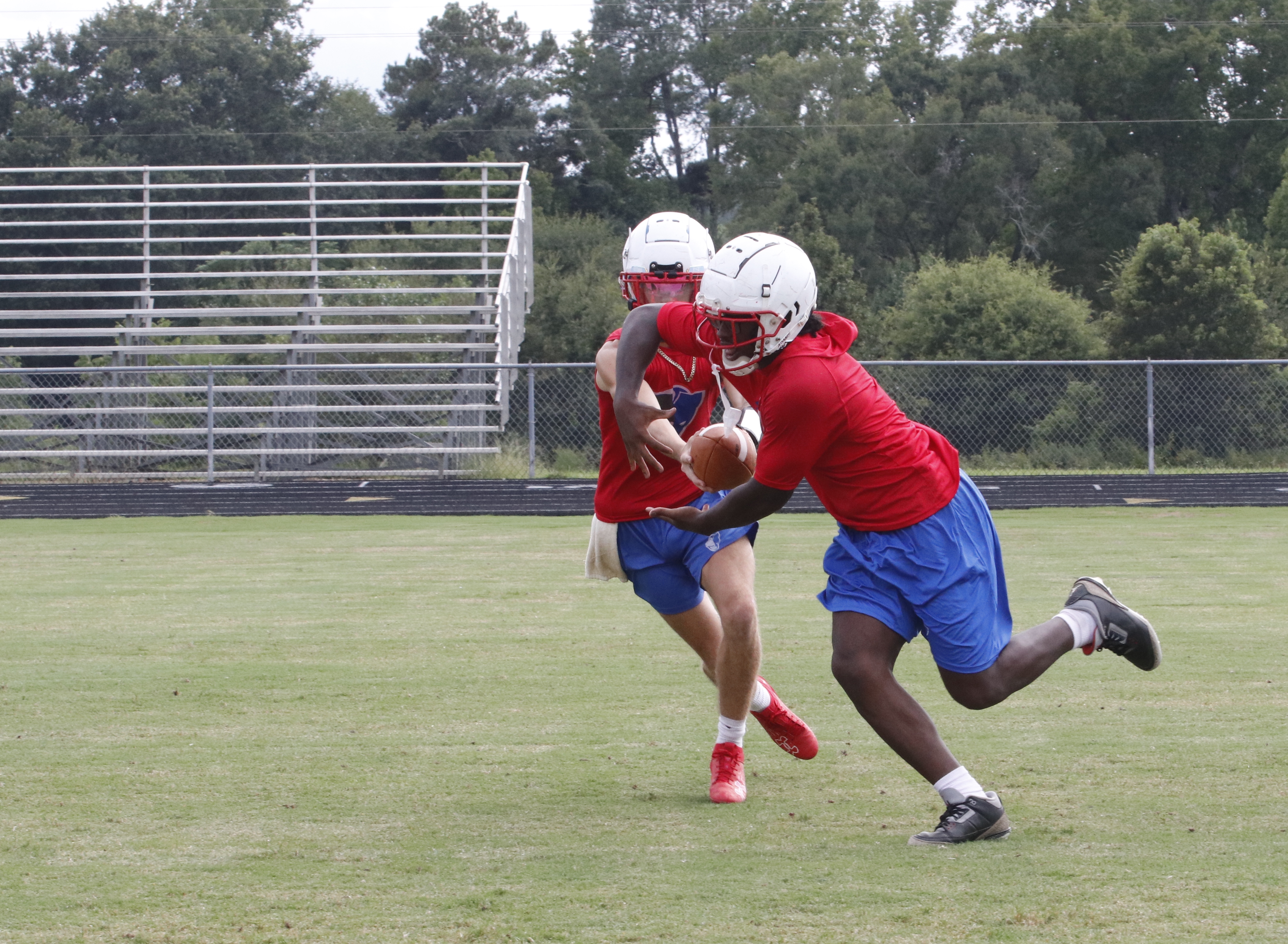 Running back O’Maury Huggs takes the ball from quarterback Caden Hartrum during practice this week. The Patriots are running a pistol wing-T offense this season that features three backs. (Photo/Andy Johnston)