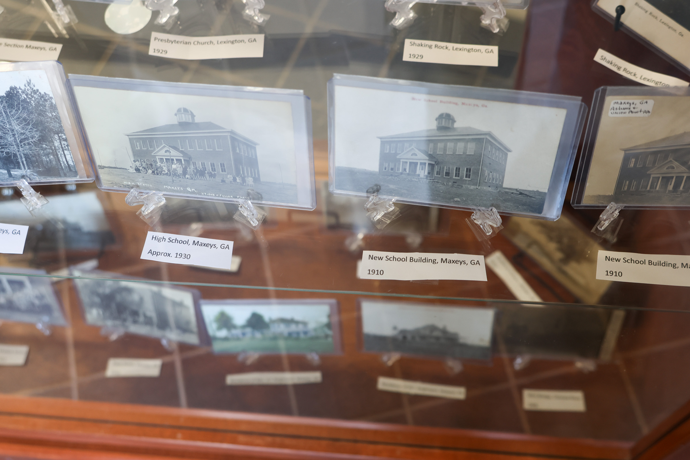 Early 20th century postcards of a school building in Maxeys sit in a display case at the Oglethorpe County Library. Several of the postcards feature images that were not used for any other purpose other than the postcard. (Photo/Susanna Johnson)