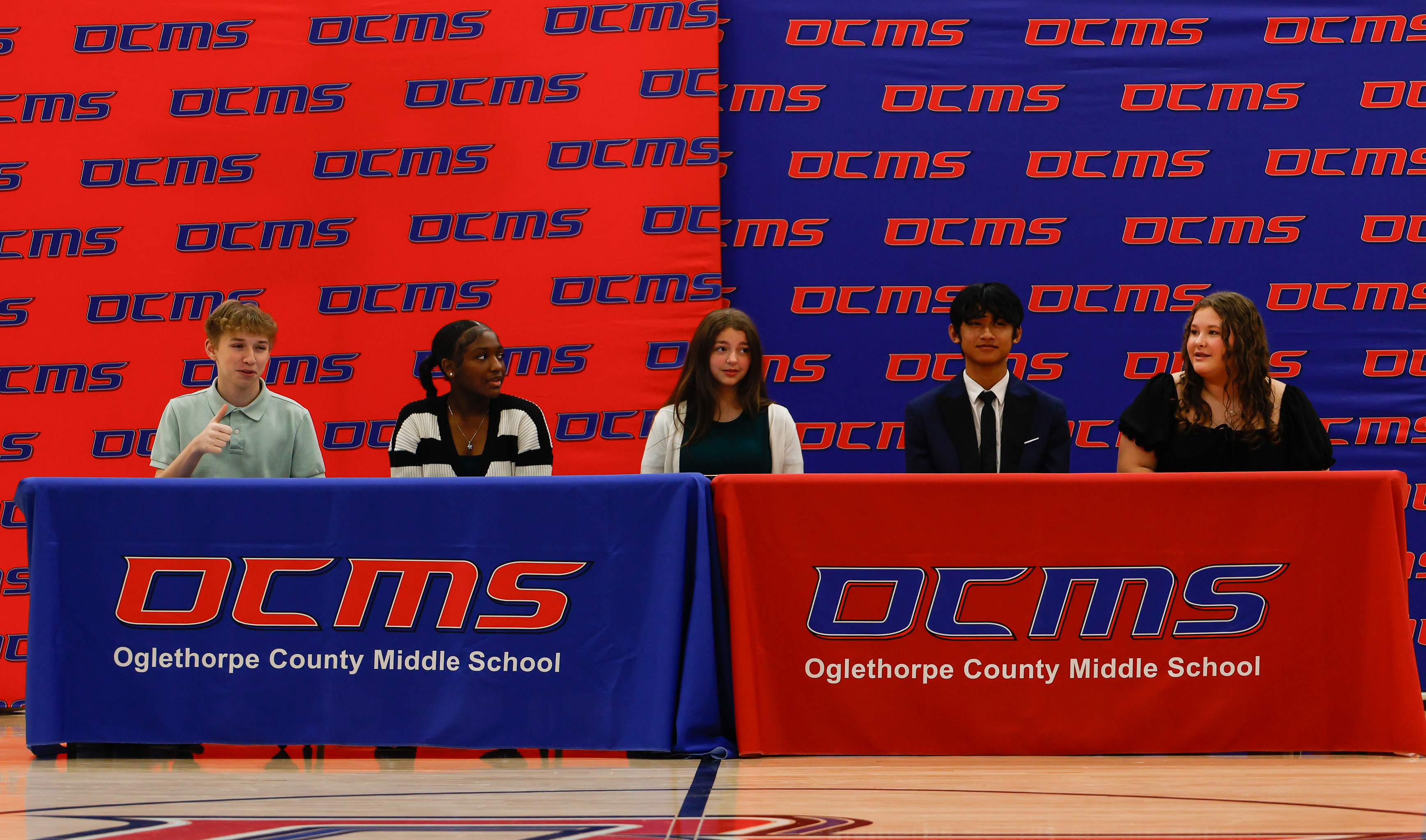 All five REACH Georgia scholars (Silas Judson, Nevaeh Perry, Elizabeth Randolph, Eh Way,  Haleigh York) sit at the signing table before finalizing their contracts on Friday, Nov. 14, 2025. The ceremony represents the culmination of a months-long selection process. (Photo / Drew Bearden)