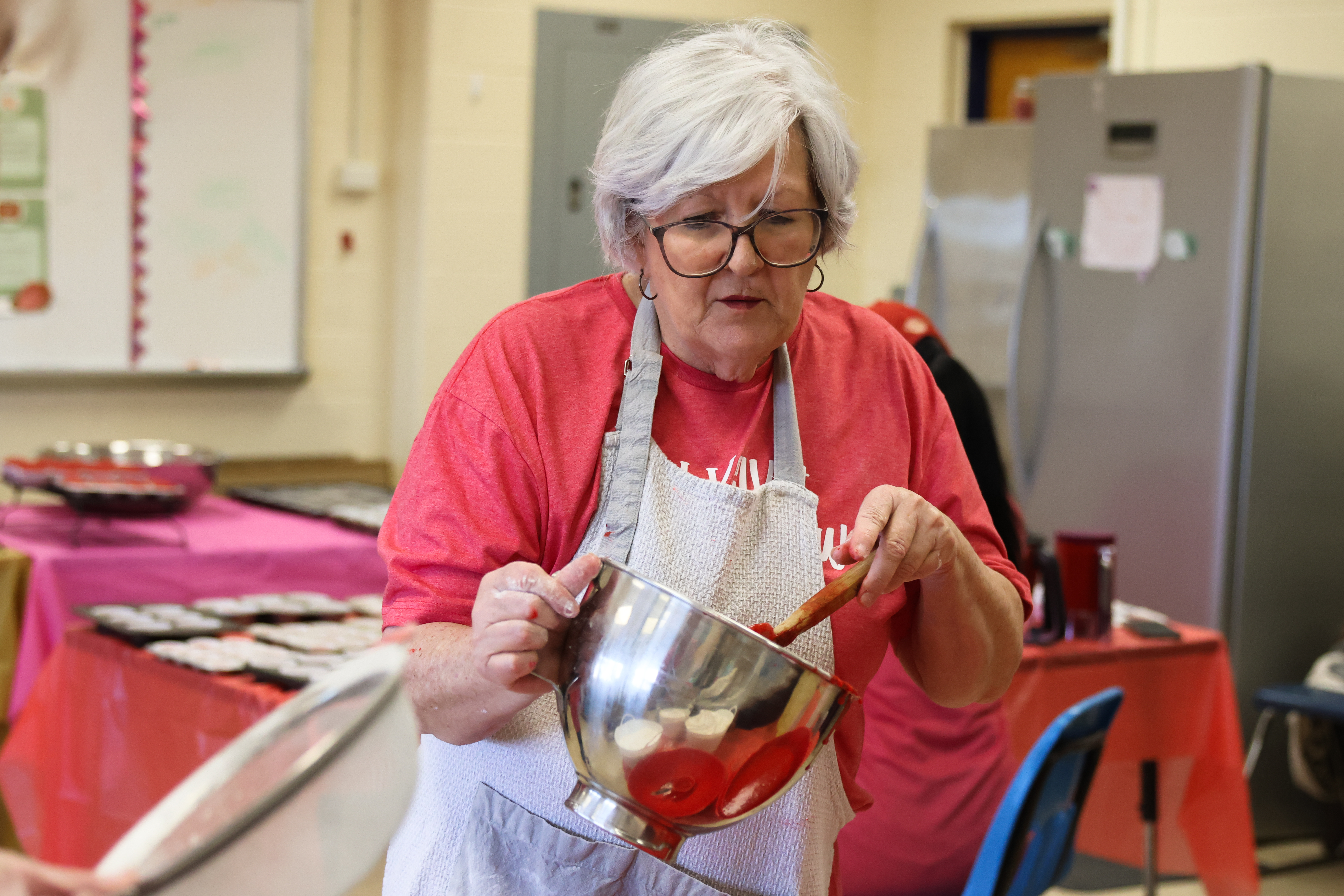 Jo Harrison transfers completed cupcake batter into a bowl for the CAYA House annual Valentine's Day fundraiser on Friday, Feb. 13, 2026, in Lexington, Georgia. Every year, Harrison has returned to help her daughter, Jill Kort, bake cupcakes. (Photo/Sydney Shankman)