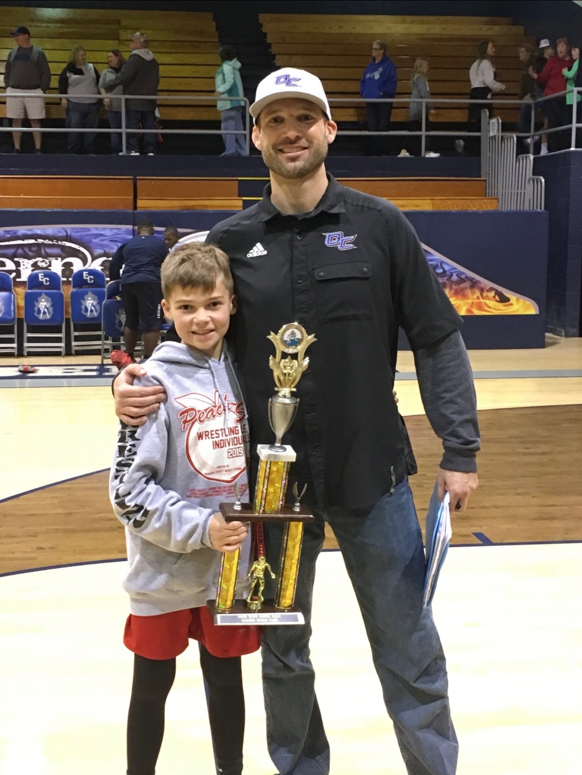Miles Mason stands with his dad, Steve Mason, after a wrestling match. Steve coached Miles for five years of his career. (Submitted photo)