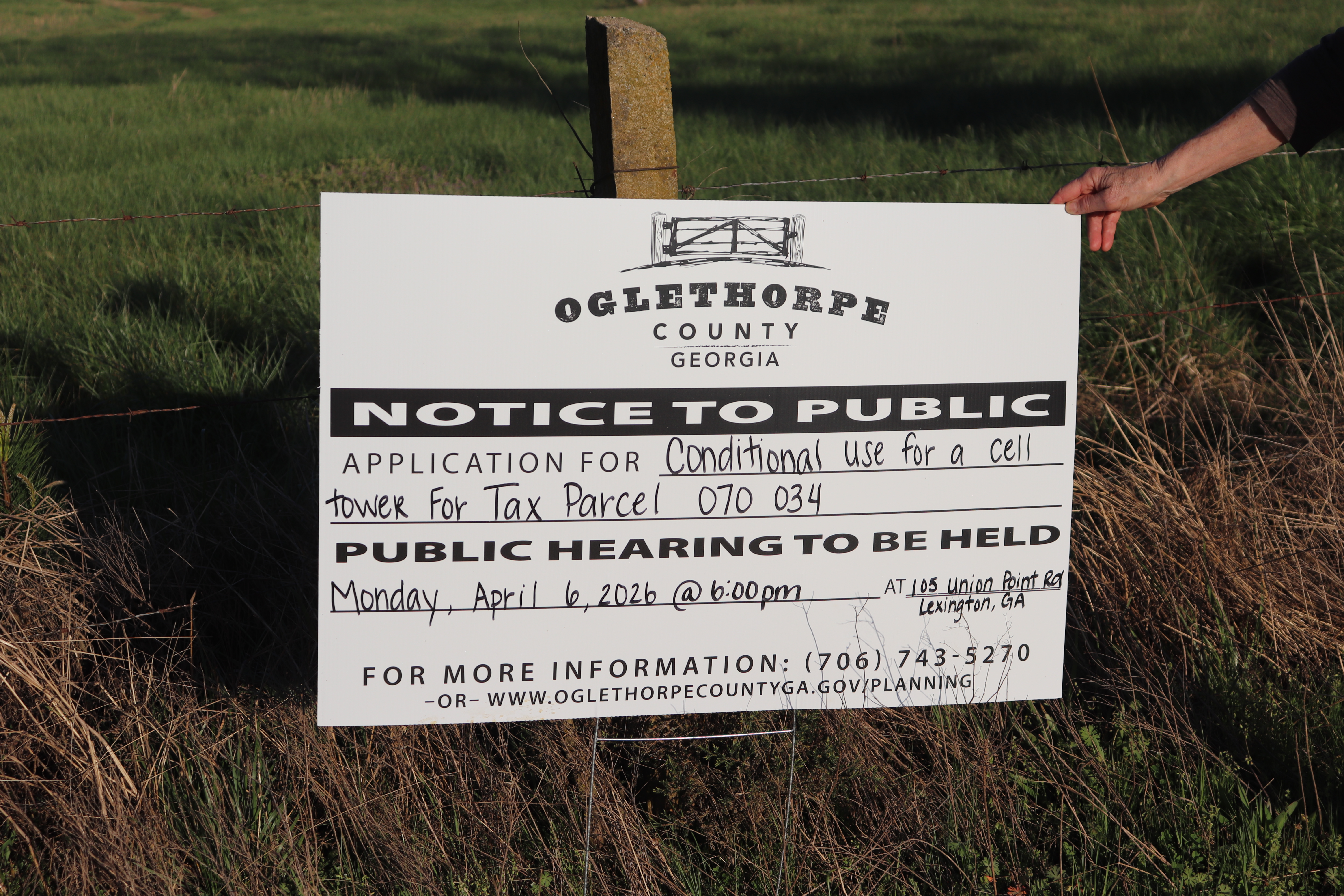A public notice sign for the cell tower stands along 202 Bowen Farm Road in Oglethorpe County, Georgia, on March 23. The tower is proposed to be built beyond the sign in the open land behind. (Photo/Emilie Sullivan)