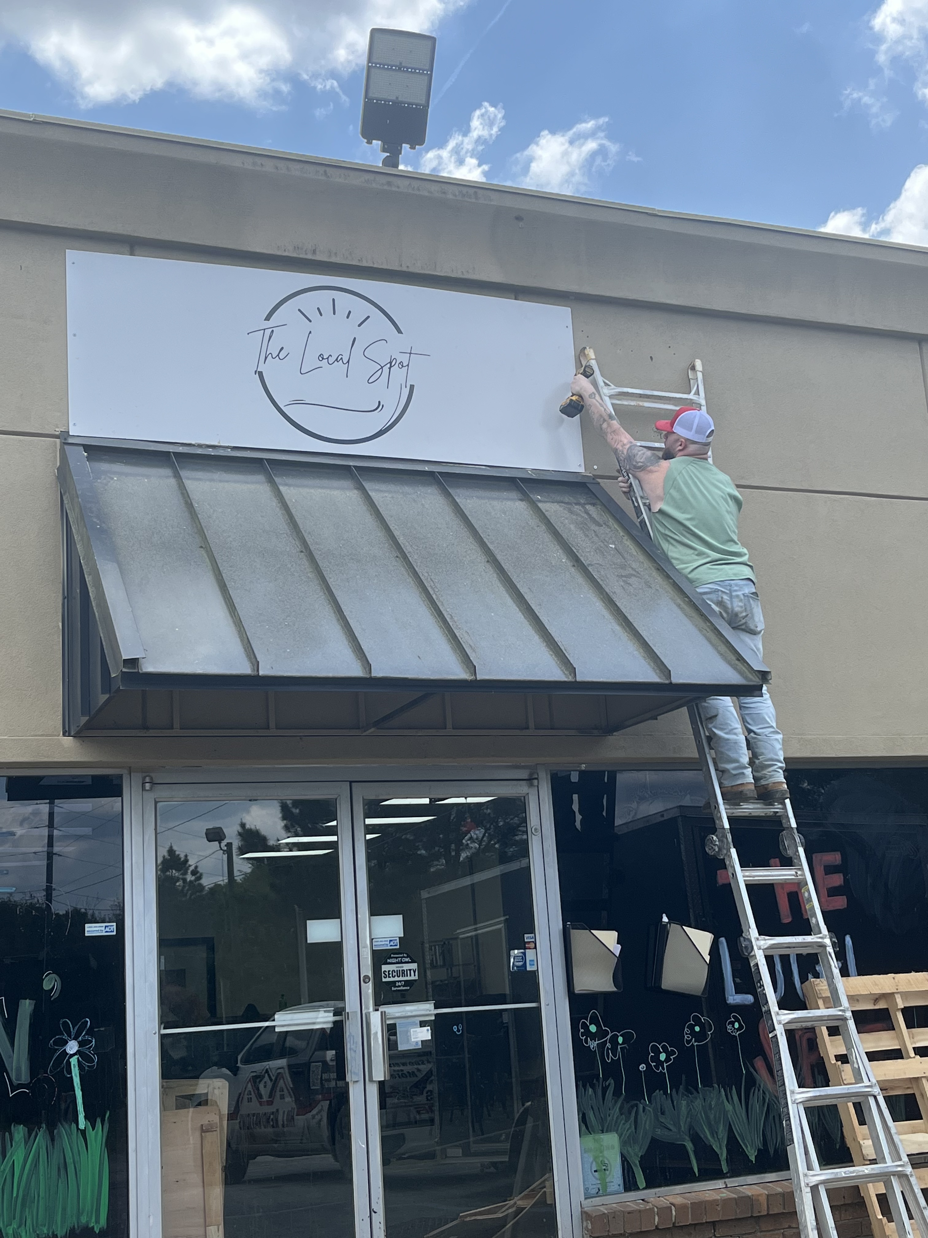 Travis Hill, owner of Hill Renovations, hangs up 'The Local Spot' sign outside. The restaurant is located at 1185 Athens Road, and planned to open late April. (Photo Submitted)