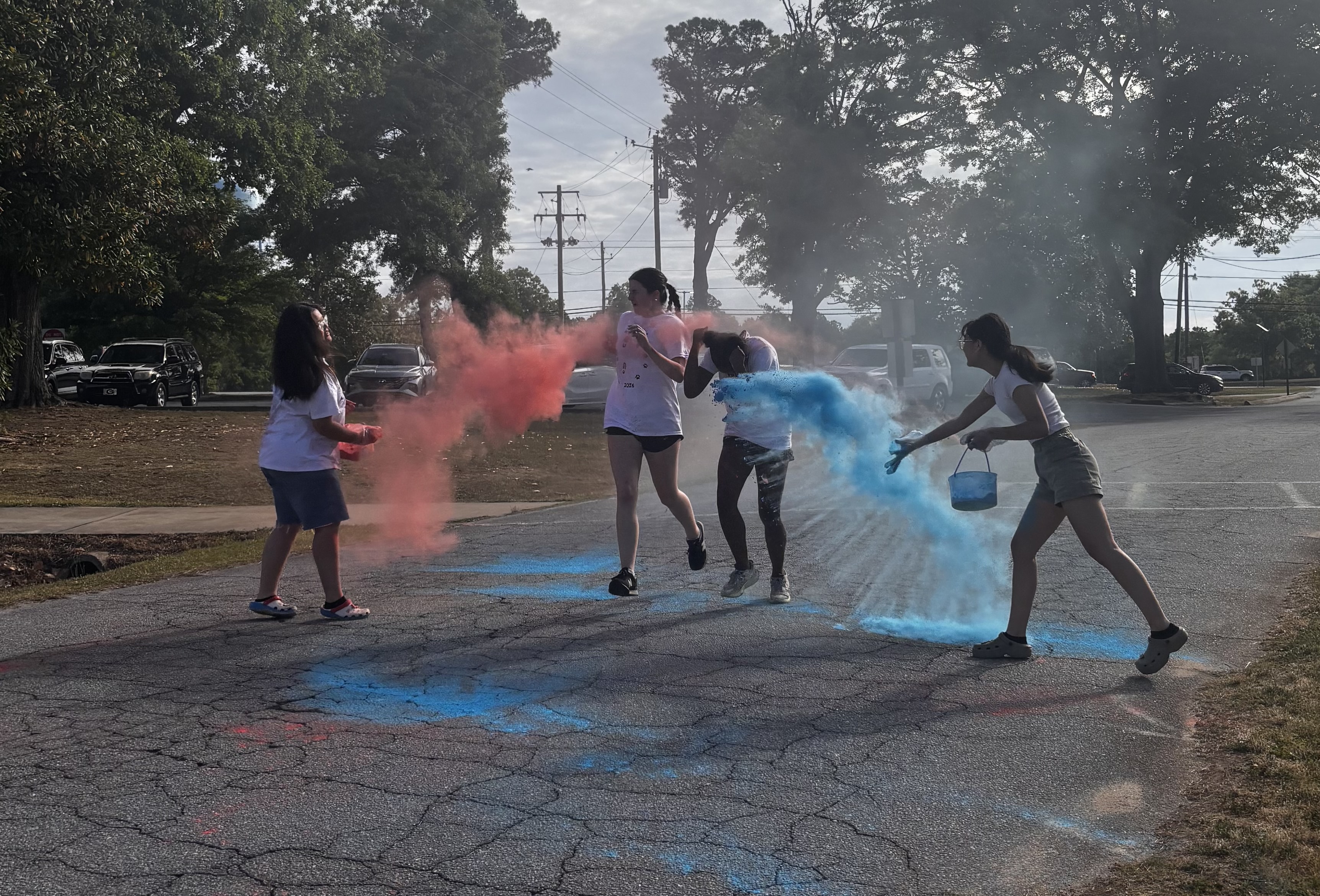 Gloria Hgay and Ellen Hgay, students at OCHS and members of the National Honor Society, throw blue and red colored powder at two race participants during the OCHS National Honor Society Color Fun Run on April 25. Students and members of the National Honor Society received service hours for participating in the race, counting toward the 18 hours required per semester to maintain membership. (CHARLOTTE COCHRAN/THE OGLETHORPE ECHO) 