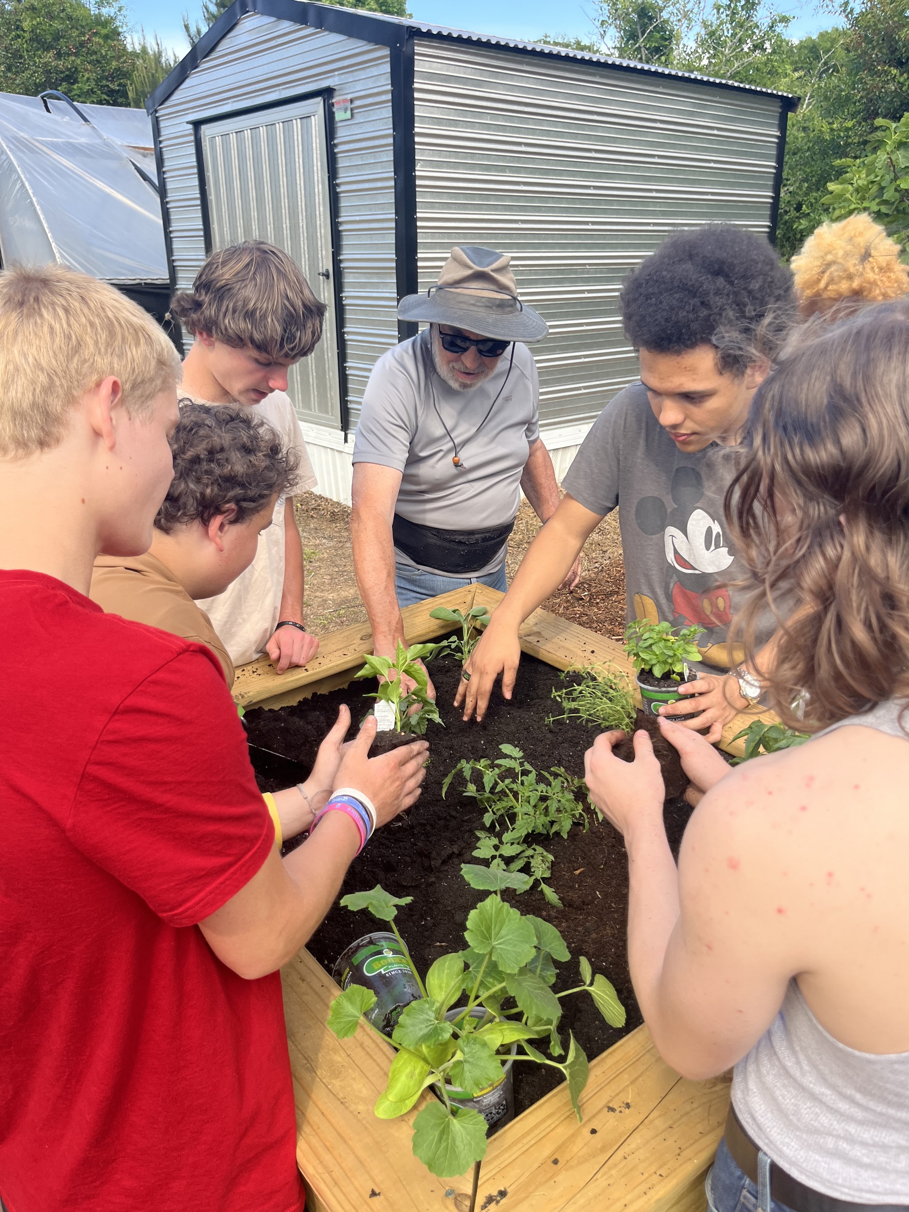 Rotary member Warren Gilson helps students place plants in gardening boxes on Tuesday at Oglethorpe County Senior Center. A wide variety of plants, including tomatoes, peppers, Zucchini squash and garden sage, were planted. (Photo/Emilie Sullivan)