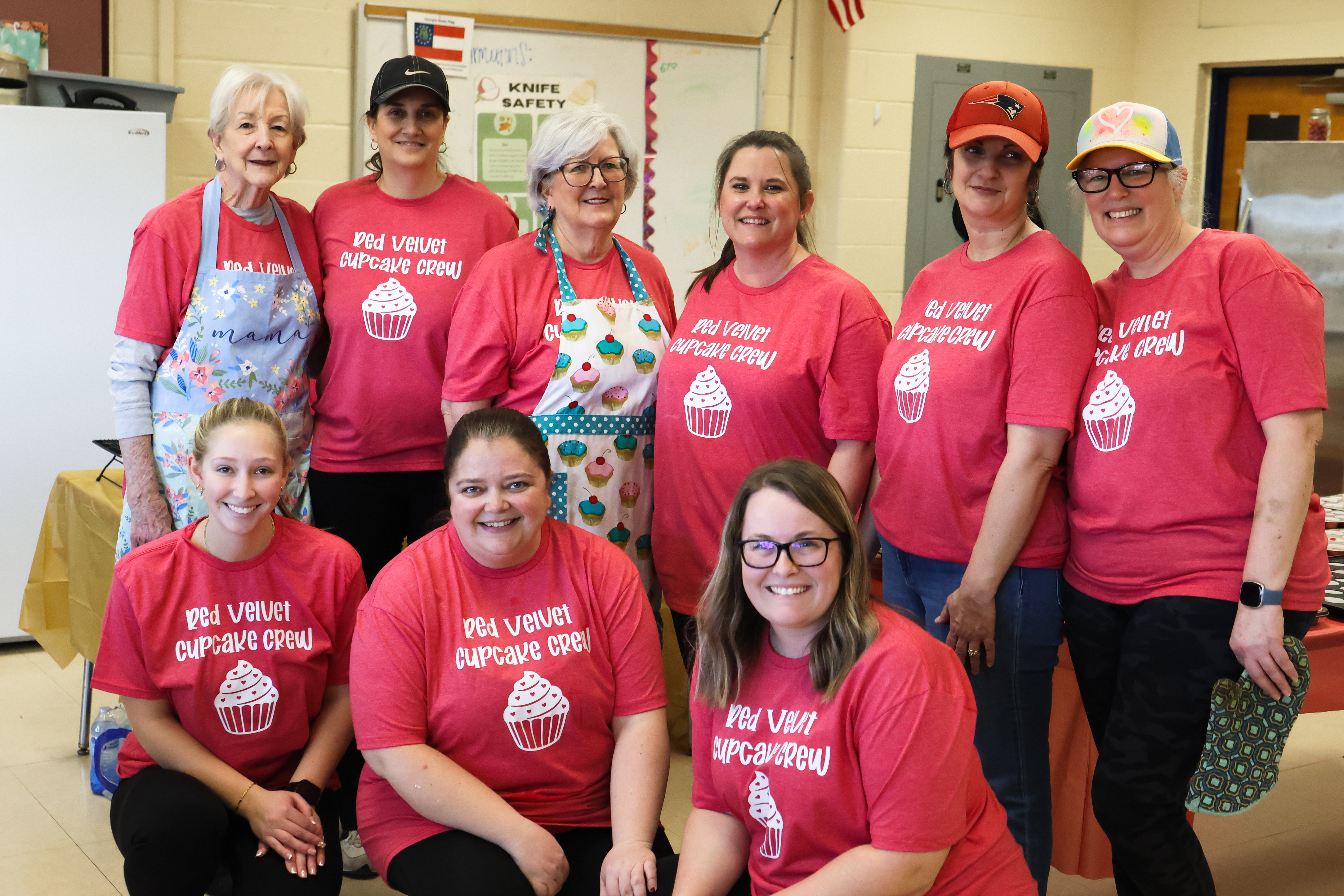 From left: Jennie Sturgis, Lisa Autry, Jo Harrison, Jill Kort, Mandie Faust, Jennifer Frost, Emilee Cutsail, Becky Soto and Kasey Taylor pose for a photo on Friday, Feb. 13, 2026, in Lexington, Georgia. The group arrived at Oglethrope County High School at 7 a.m. to begin baking and planned to bake into the evening. (Photo/Sydney Shankman) 