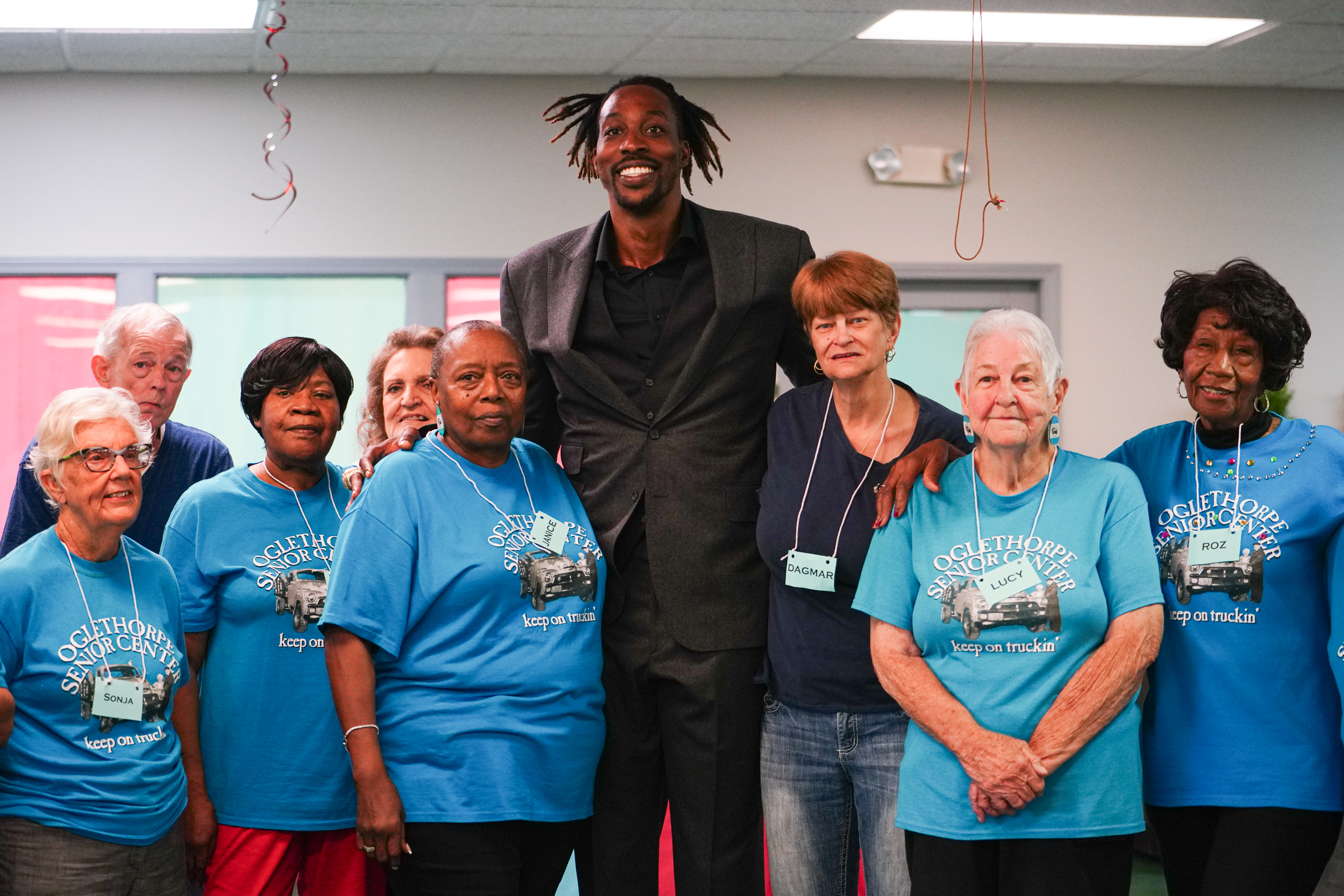 NBA All Star Dwight Howard poses with blue team members (left to right) Sonja Armour, Dan Moore, Lynda Jones, Pam Compton, Janice Brown, Dagmarr Star, Lucy McCannon and Roz Echols on Friday. NBA All Star Dwight Howard hosted 'Family Feud' at the Oglethorpe Senior Center in Crawford, Georgia. (Sidney Chansamone/The Oglethorpe Echo)