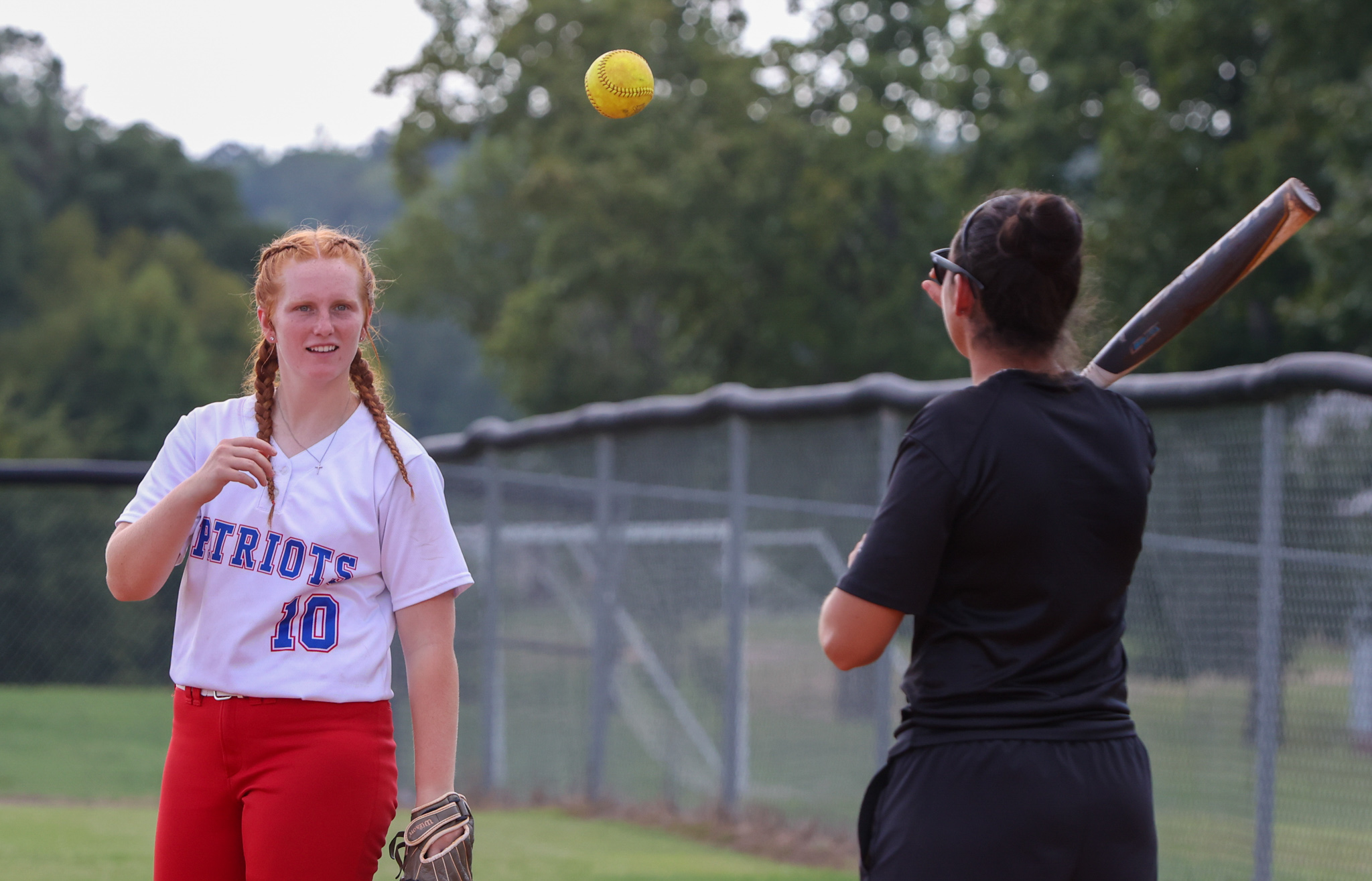 Senior catcher Abby Jones and Oglethorpe County High School softball head coach Brianna Dickens serve balls to the other players during warmups ahead of the team's 7-3 loss to Washington-Wilkes Comprehensive High School on Thursday, August 31, 2023, in Lexington, Georgia. The softball team celebrated Jones as its only senior during its Senior Night celebrations prior to the game. (Photo/Cassidy Hettesheimer)