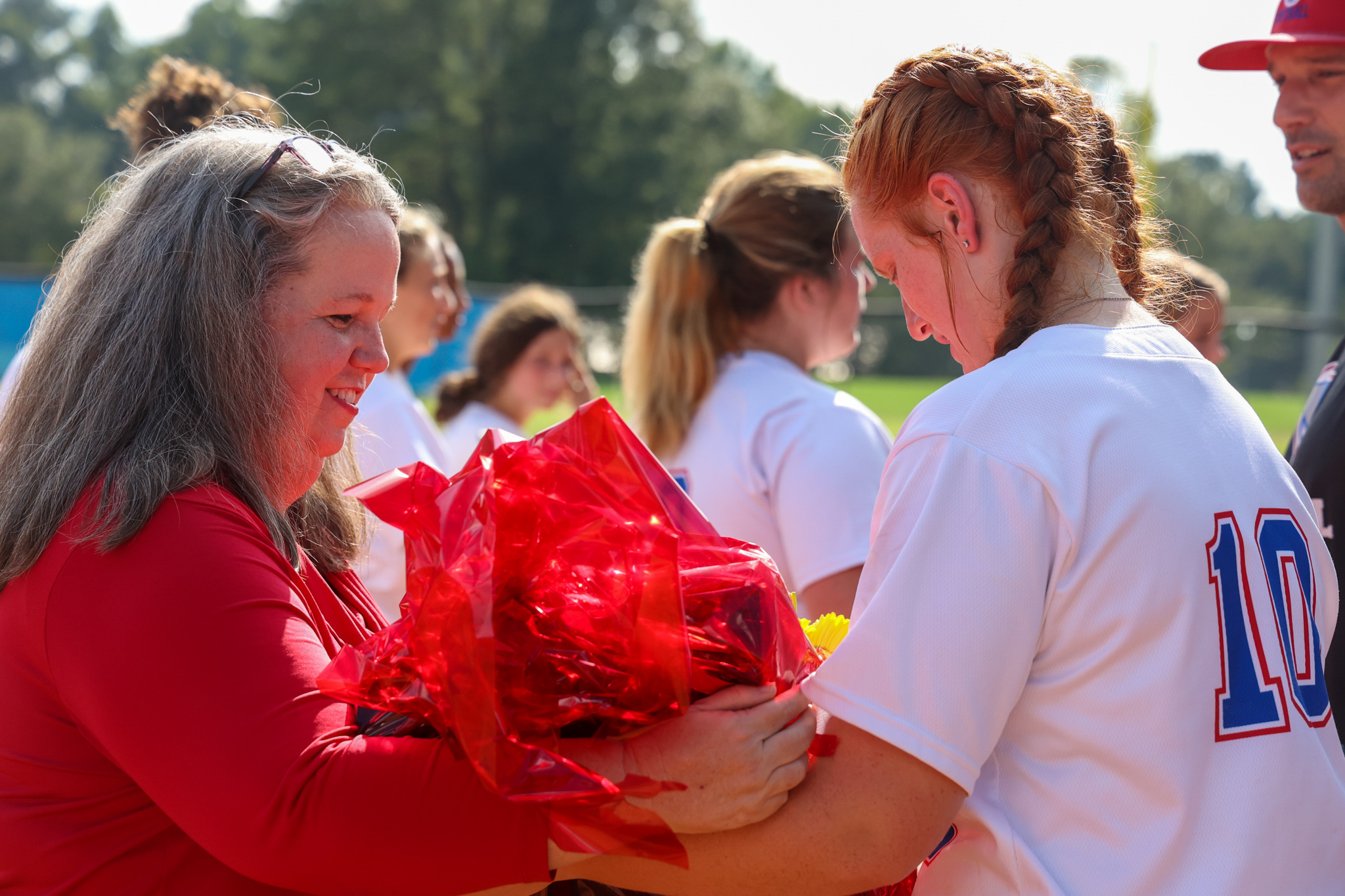 Senior catcher Abby Jones passes a framed jersey to her mom after the Oglethorpe County High School softball Senior Night celebrations on Thursday, August 31, 2023, in Lexington, Georgia. The softball team celebrated Jones as its only graduating senior during its Senior Night celebrations prior to its game against Washington-Wilkes. (Photo/Cassidy Hettesheimer)