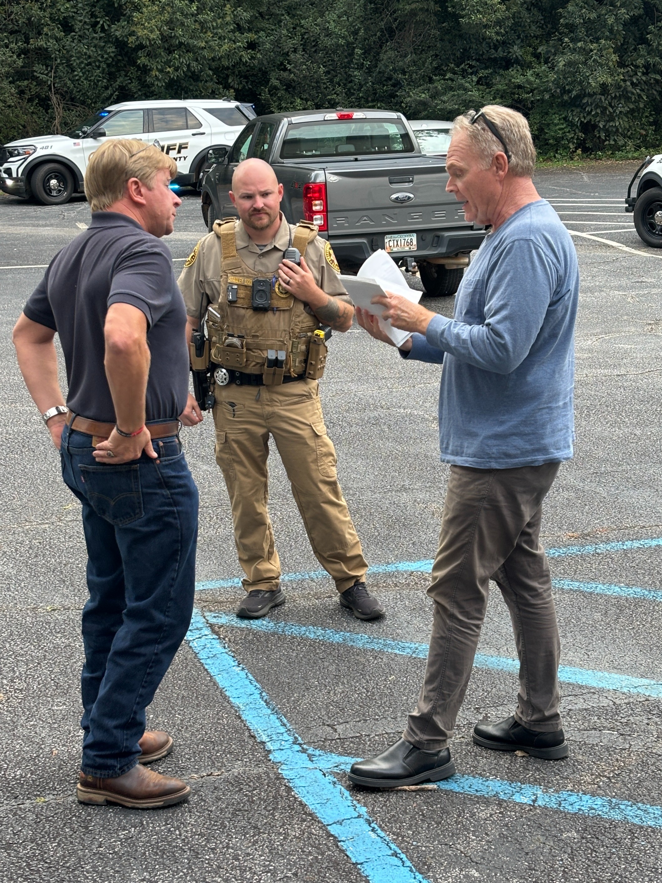 Oglethorpe County Deputy Dustin Stanley listens to Commission Chair Jay Paul (left) and Crawford resident Scott Pettis in the parking lot outside the Board of Commissioners meeting room on Monday. Stanley was one of three deputies who responded to a verbal altercation between Pettis and Board of Education member Jake Willcox after the meeting. Pettis regularly attends the meetings to voice his displeasure with property taxes and the BOE during the public comment section, and he and Willcox had a conversation in the foyer of the building that escalated into shouting. Pettis was escorted outside and Willcox went back into the meeting room before the deputies arrived. There were no arrests. (Andy Johnston/The Oglethorpe Echo)
