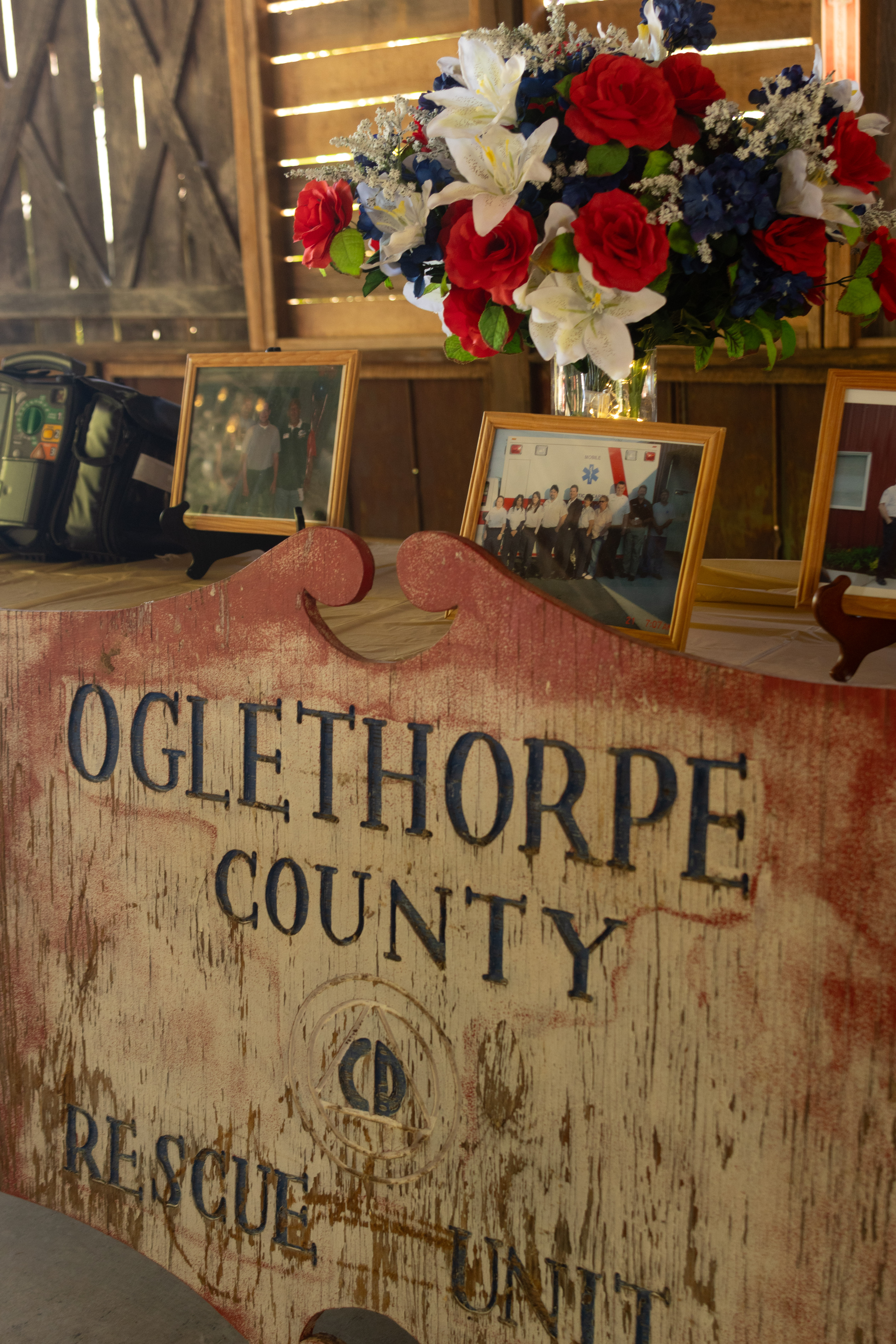 Oglethorpe County rescue unit sign propped against a table holding photos and multiple iterations of defibrillator equipment at the EMS 50th anniversary celebration on Friday, Oct. 23, 2026. The table includes photos of past units as well as defibrillators from 1988 to 2024. (SARAH ROPER/THE OGLETHORPE ECHO)