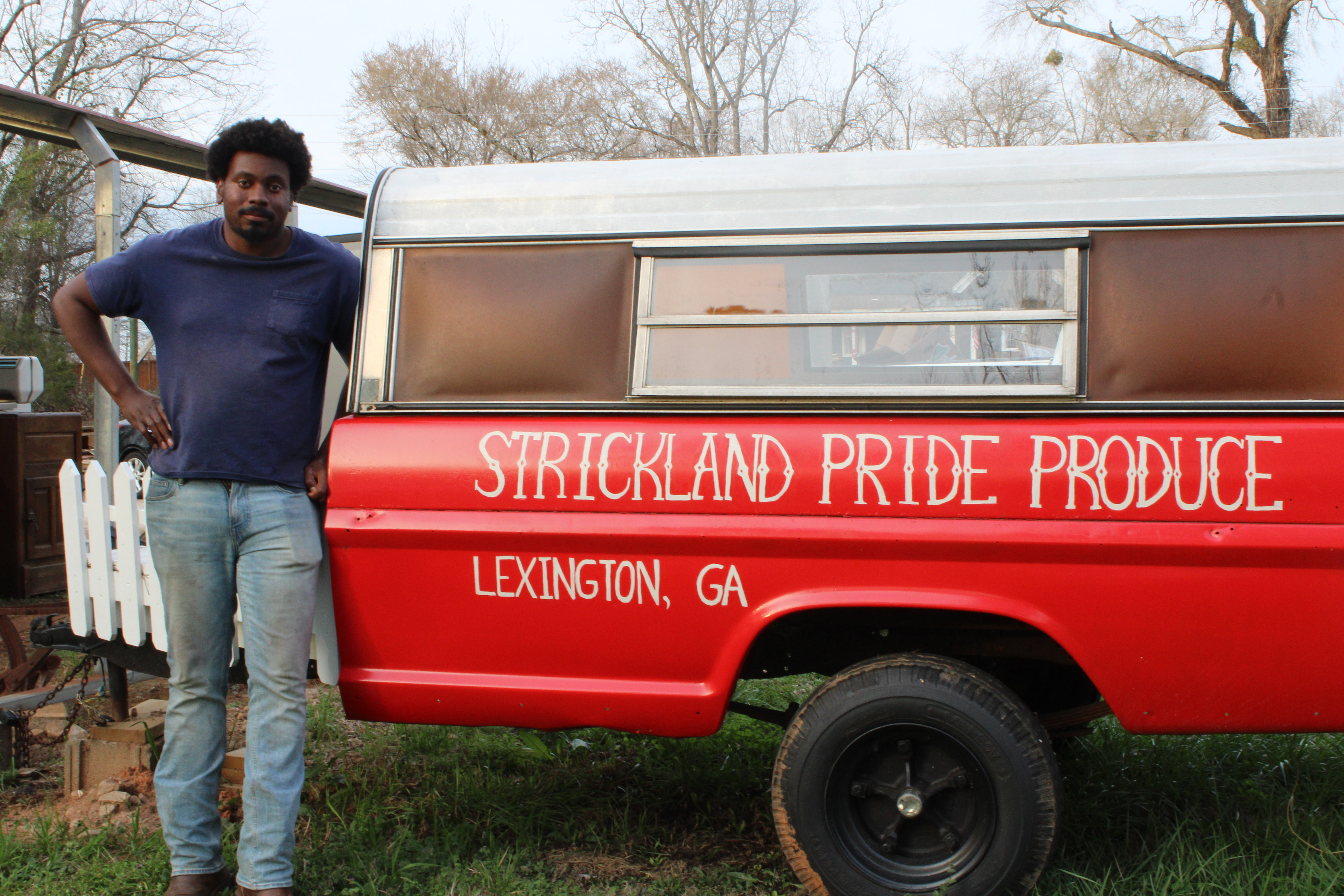 Owner, founder and operator of Strickland Pride Produce, Kendall Strickland poses for photo next to his sign. (Destiny Hartwell/The Oglethorpe Echo)