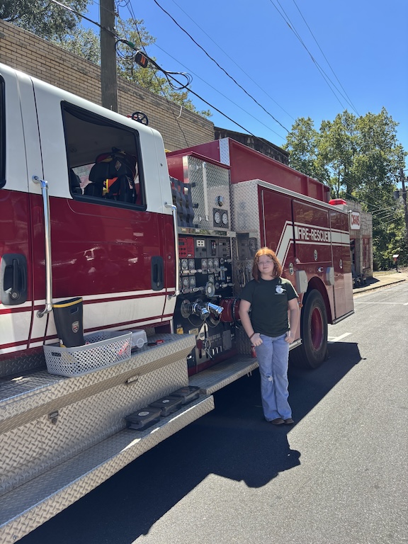 Lantie Spencer stands in front of the Lexington Volunteer Fire Department fire truck at the Firefly Cruise In. Spencer, 12, is the daughter of Nicole and Douglas Spencer and has been helping with the Boot Barn fundraising initiative for three years. (Maura Potvin/The Oglethorpe Echo)