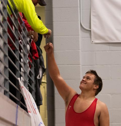 Senior Logan Steward reaches for a fan in the stands after his match. (Photo/Sarah White)