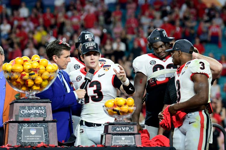 Bennett uses his scrambling DNA to avoid a Michigan defender. (Submitted Photo/Perry McIntyre, UGA Sports)