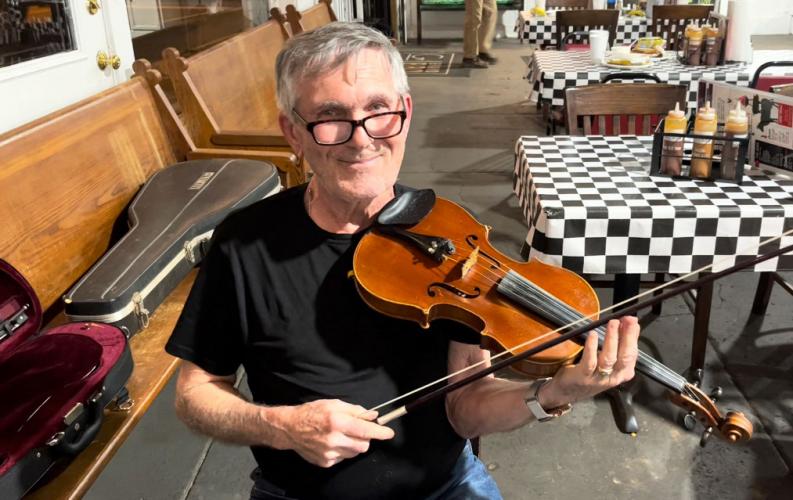 Robert Hauth poses with his fiddle at G Brand BBQ. Hauth said his bluegrass band is like a second family.  (Shannon Moran/The Oglethorpe Echo)