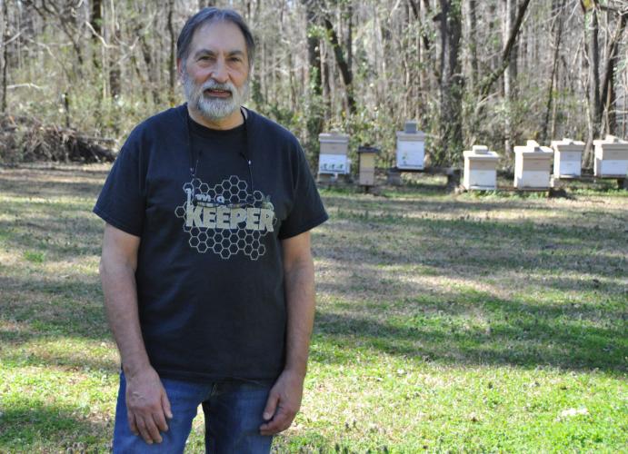 Joe Conti, president of the Oglethorpe County Bee Club, stands in front of several of the 14 hives that he keeps in his backyard. (Elena Westbury/The Oglethorpe Echo)