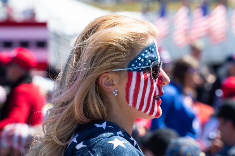 A woman identifying as Clemeen Connolly walks through the crowd at the Save America rally at the Atlanta Dragway on Saturday, March 26, 2022 in Commerce, Georgia. Connolly, from Florida, is a member of the Front Row Joes, a group that travels to nearly every rally held by the former President’s PAC. Connolly said she had been to at least four rallies. (Julian Alexander/For The Oglethorpe Echo)